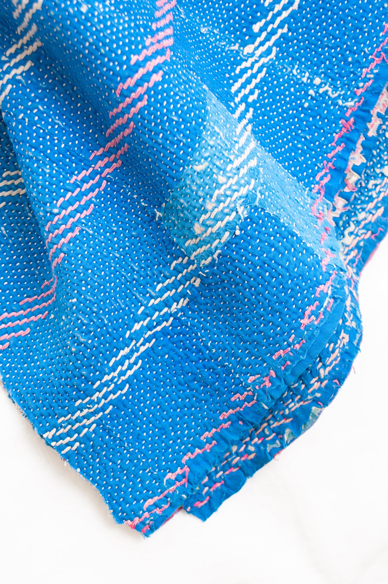 Vintage kantha quilt in cobalt blue stitched in pink and white.