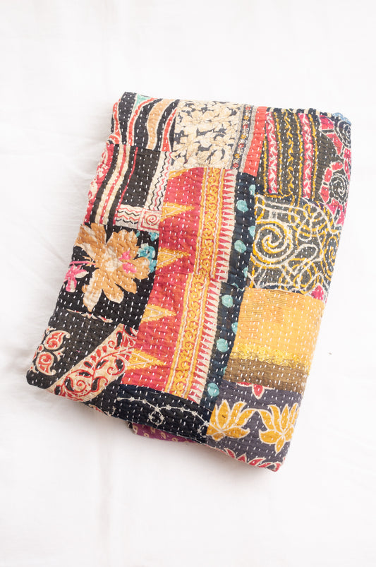 Vintage patchwork kantha quilt im multiple prints with black base.