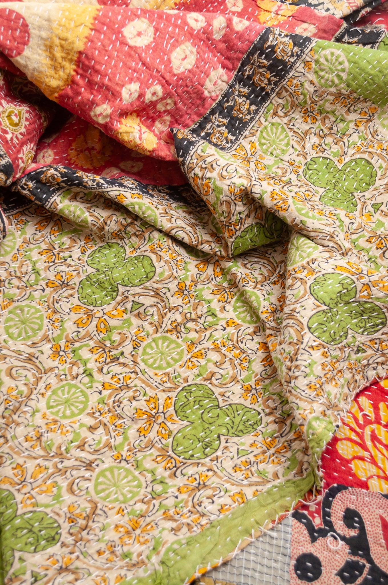 Vintage patchwork kantha quilt im multiple prints with black base.
