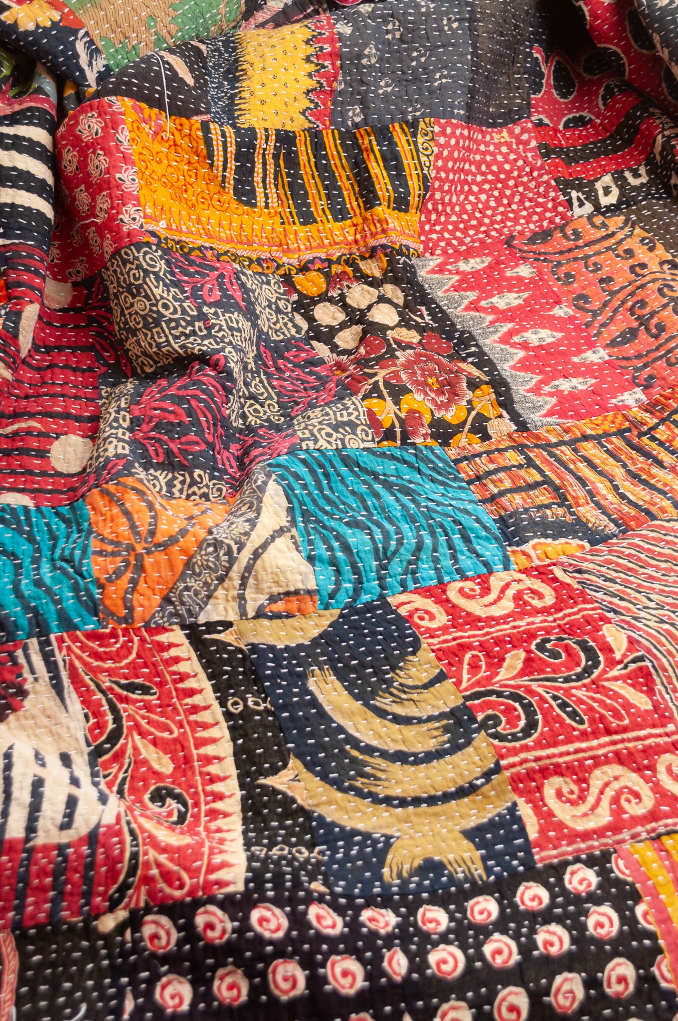 Vintage patchwork kantha quilt im multiple prints with black base.