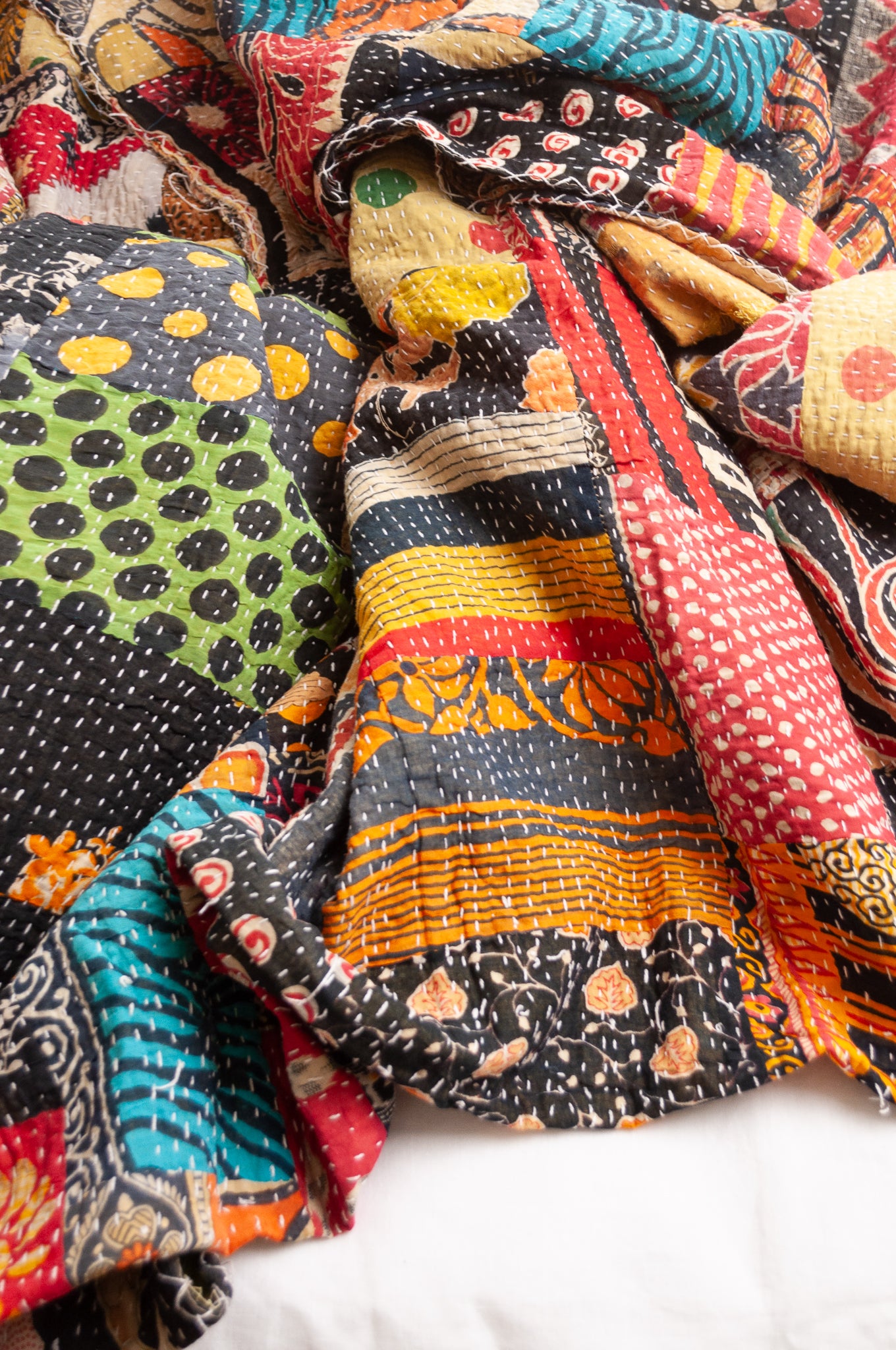 Vintage patchwork kantha quilt im multiple prints with black base.