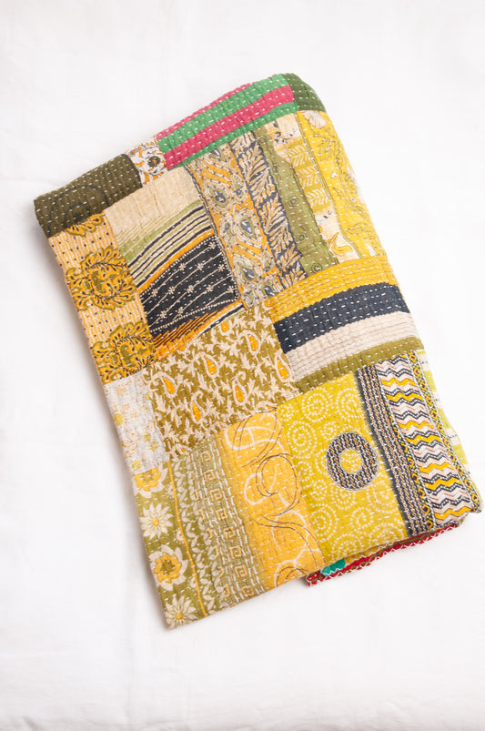 Vintage patchwork kantha quilt in multiple prints with green base.