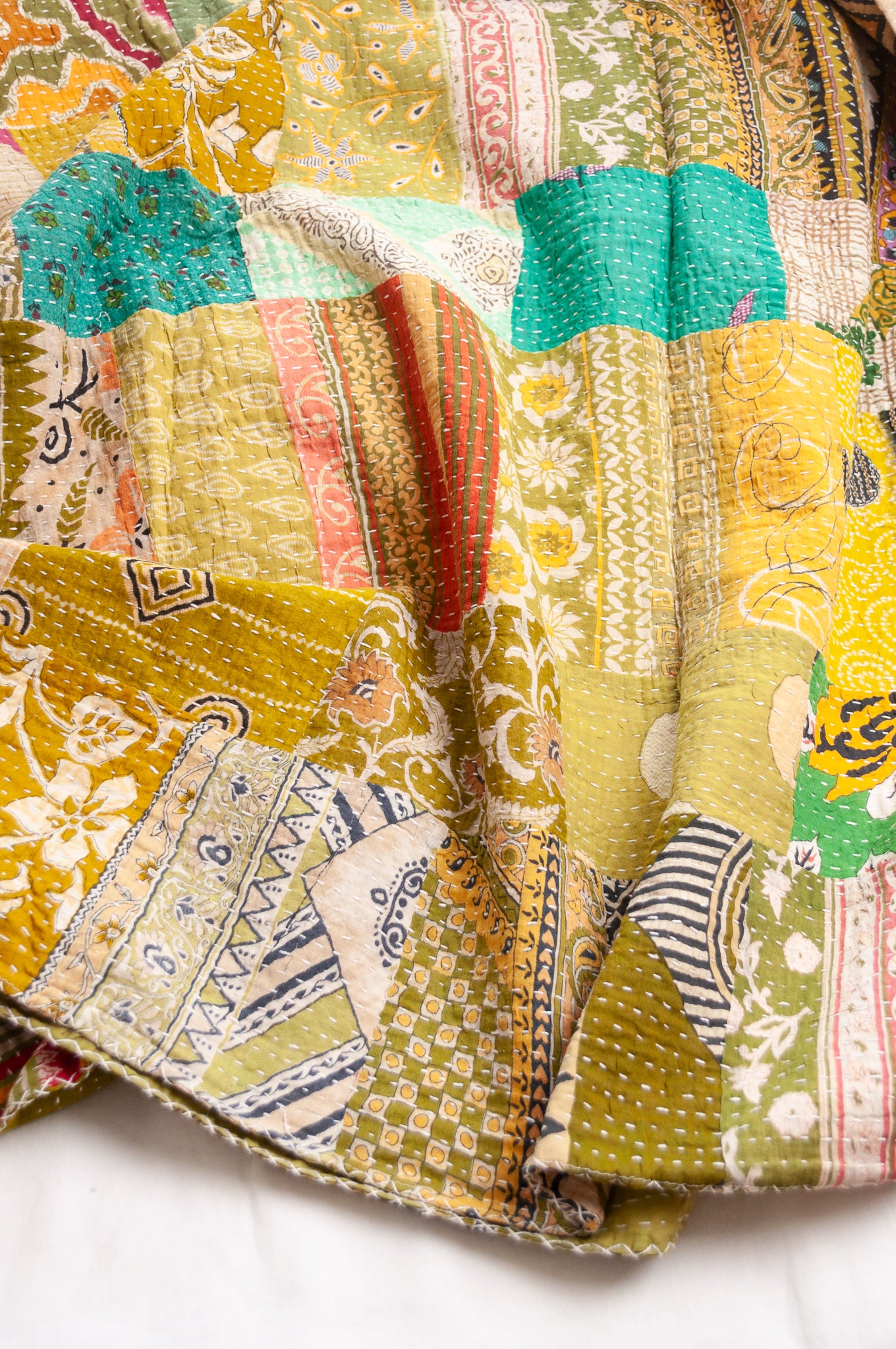 Vintage patchwork kantha quilt in multiple prints with green base.