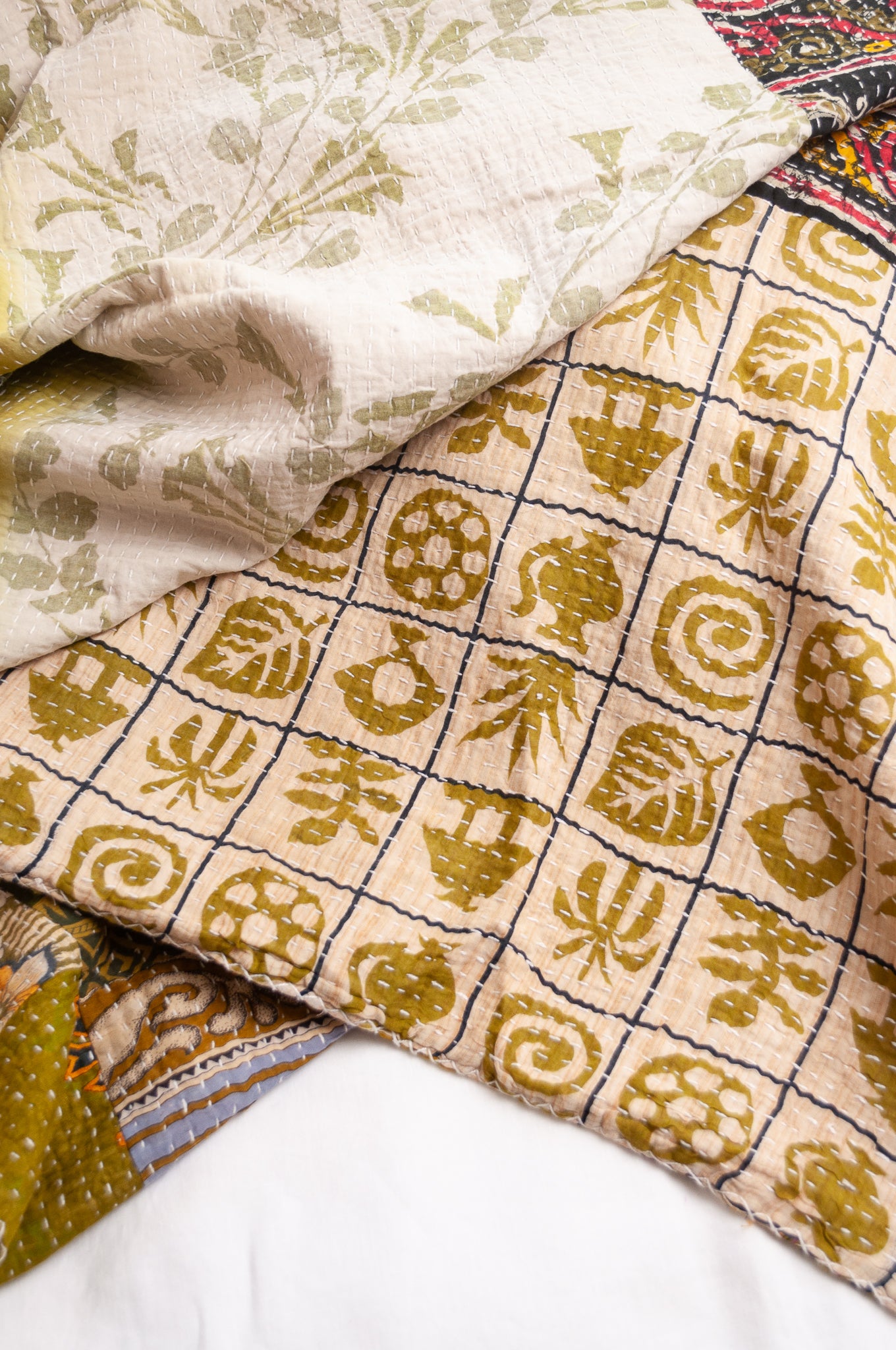 Vintage patchwork kantha quilt in multiple prints with green base.