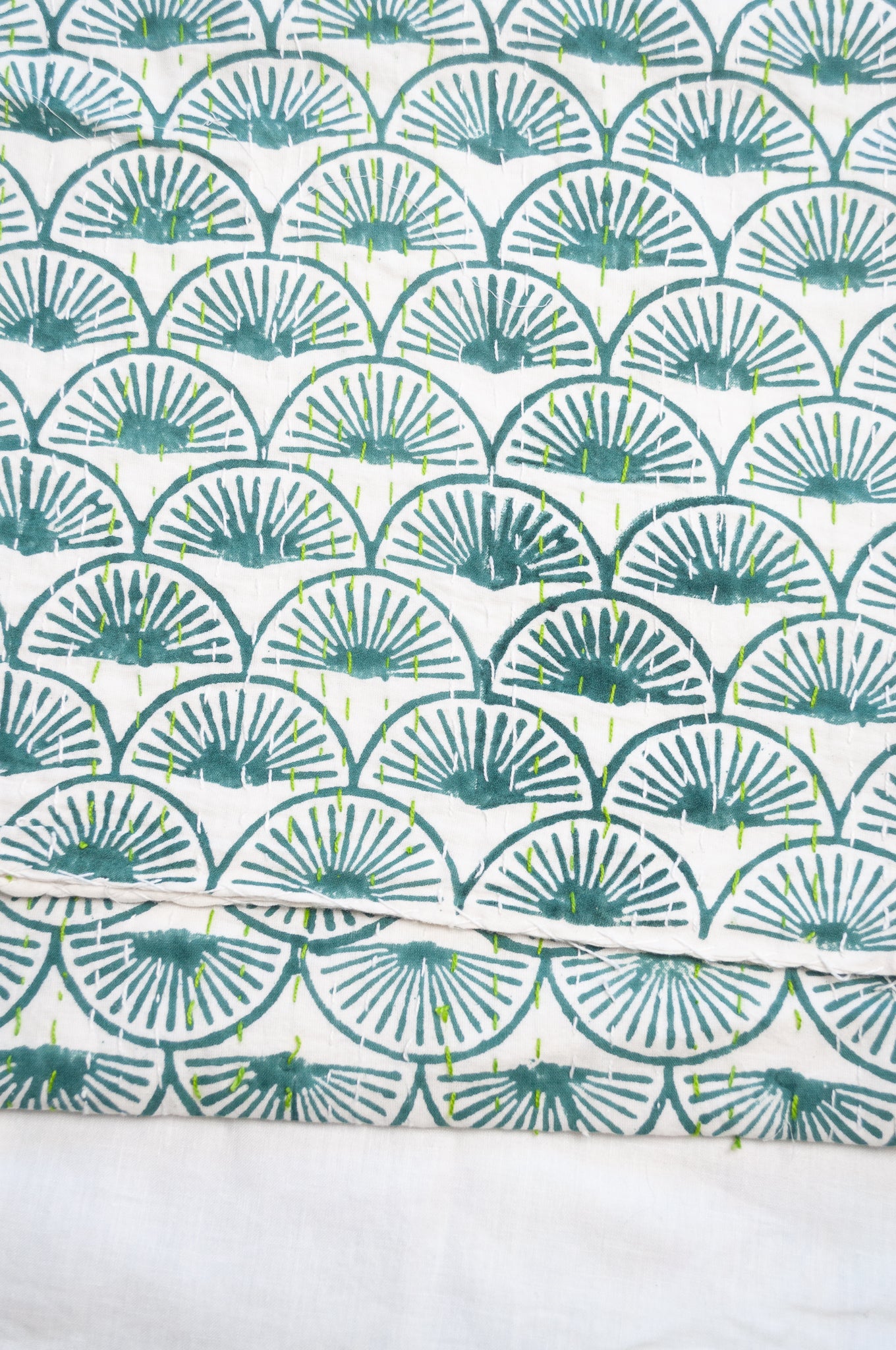 Cotton kantha quilt in teal green fans on white.