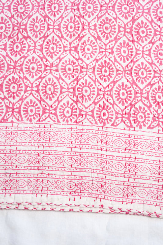 Cotton kantha quilt with an abstract floral design in pink on white.