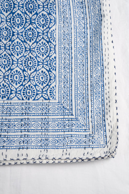 Cotton kantha quilt with an abstract floral design in blue on white.