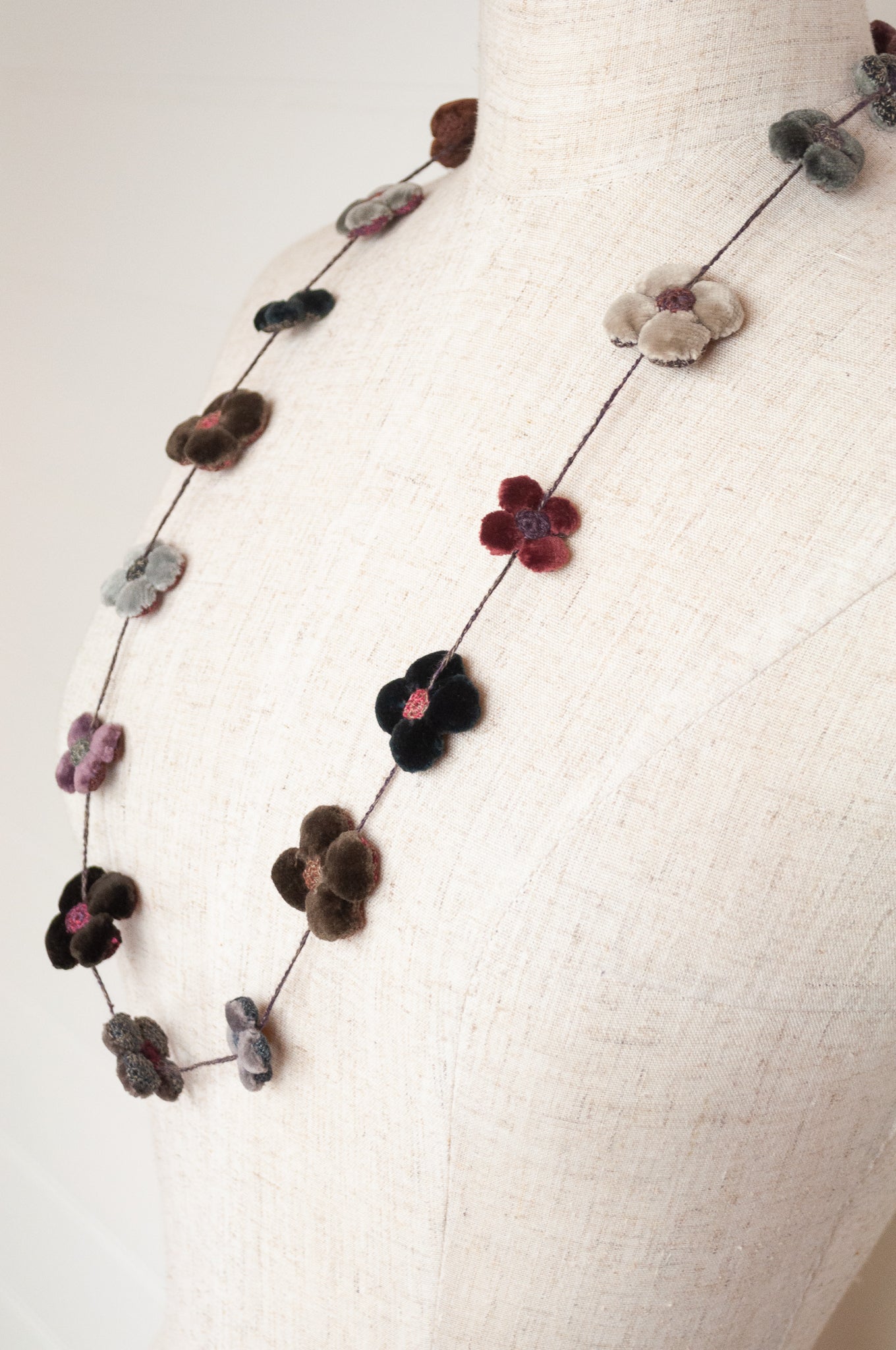 Classic handmade Sophie Digard necklace is a string of beautiful velvet flowers, backed with linen embroidery in a cool winter palette, Dingle.