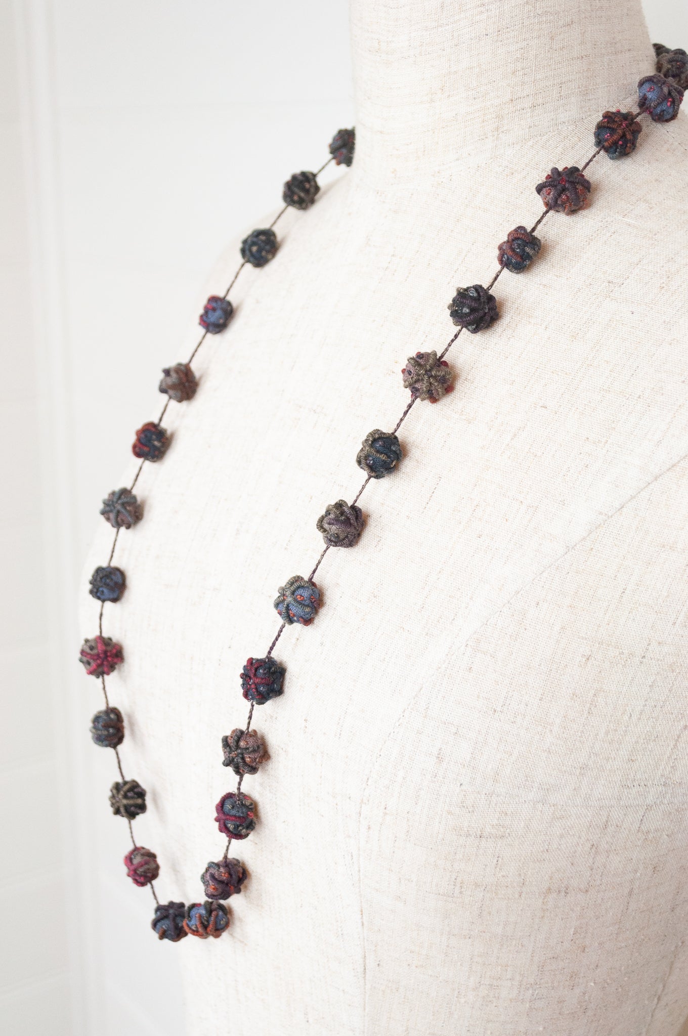 Classic handmade Sophie Digard necklace is a string of embroidered fabric beads, in a cool winter palette, Dingle.