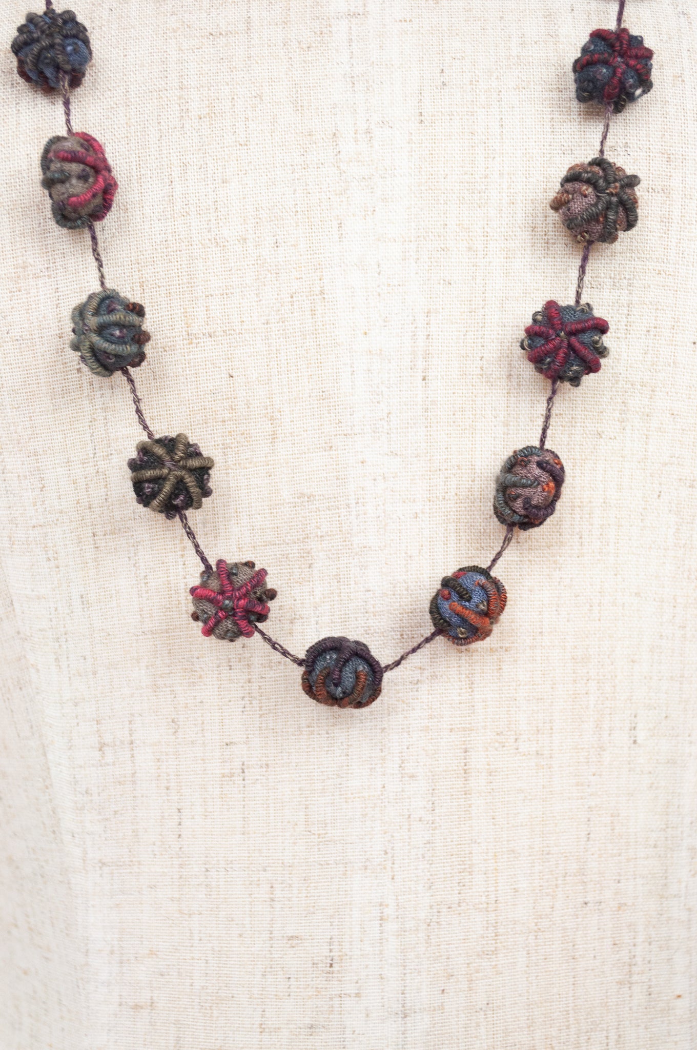 Classic handmade Sophie Digard necklace is a string of embroidered fabric beads, in a cool winter palette, Dingle.