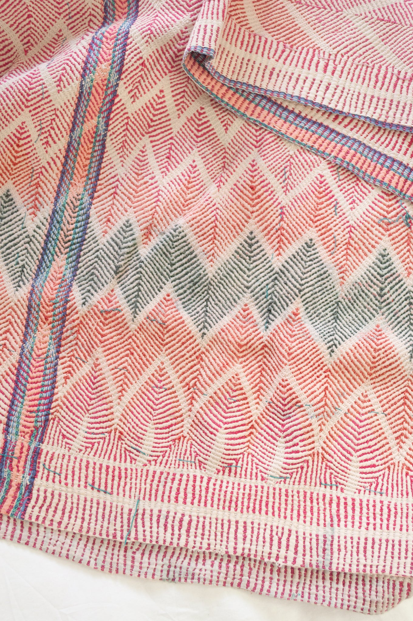 Vintage lohori wave stitched kantha quilt in red, pink, green and blue on white.