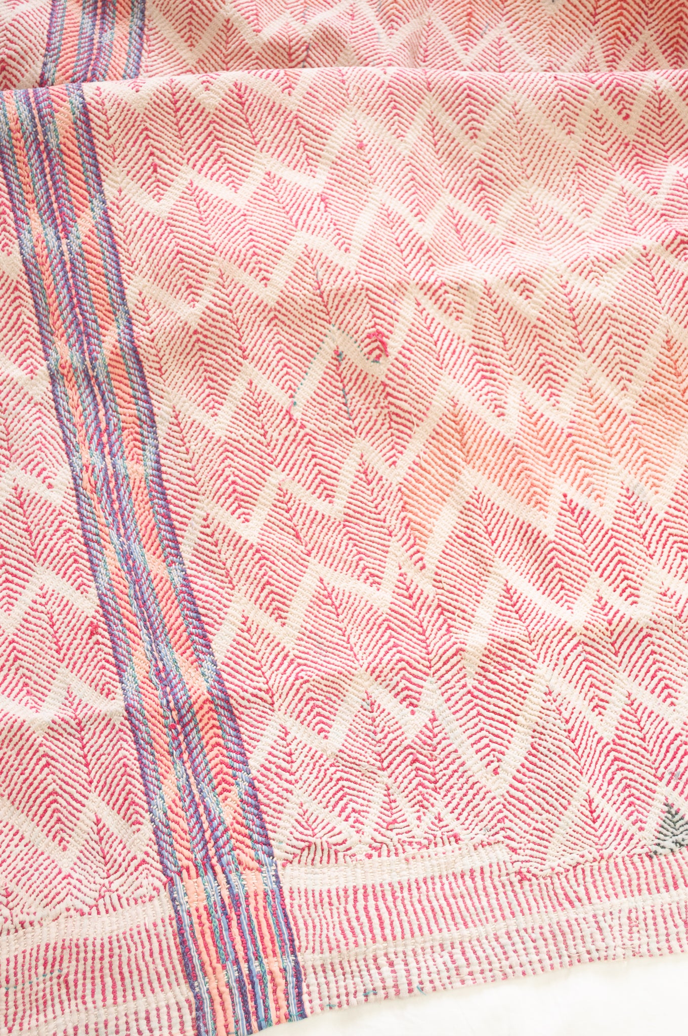Vintage lohori wave stitched kantha quilt in red, pink, green and blue on white.