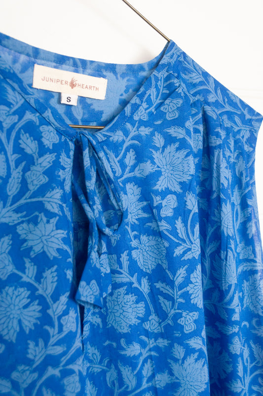 Juniper Hearth Stella dress in cornflower blue blockprint floral cotton, A-line sleeveless with front ties.