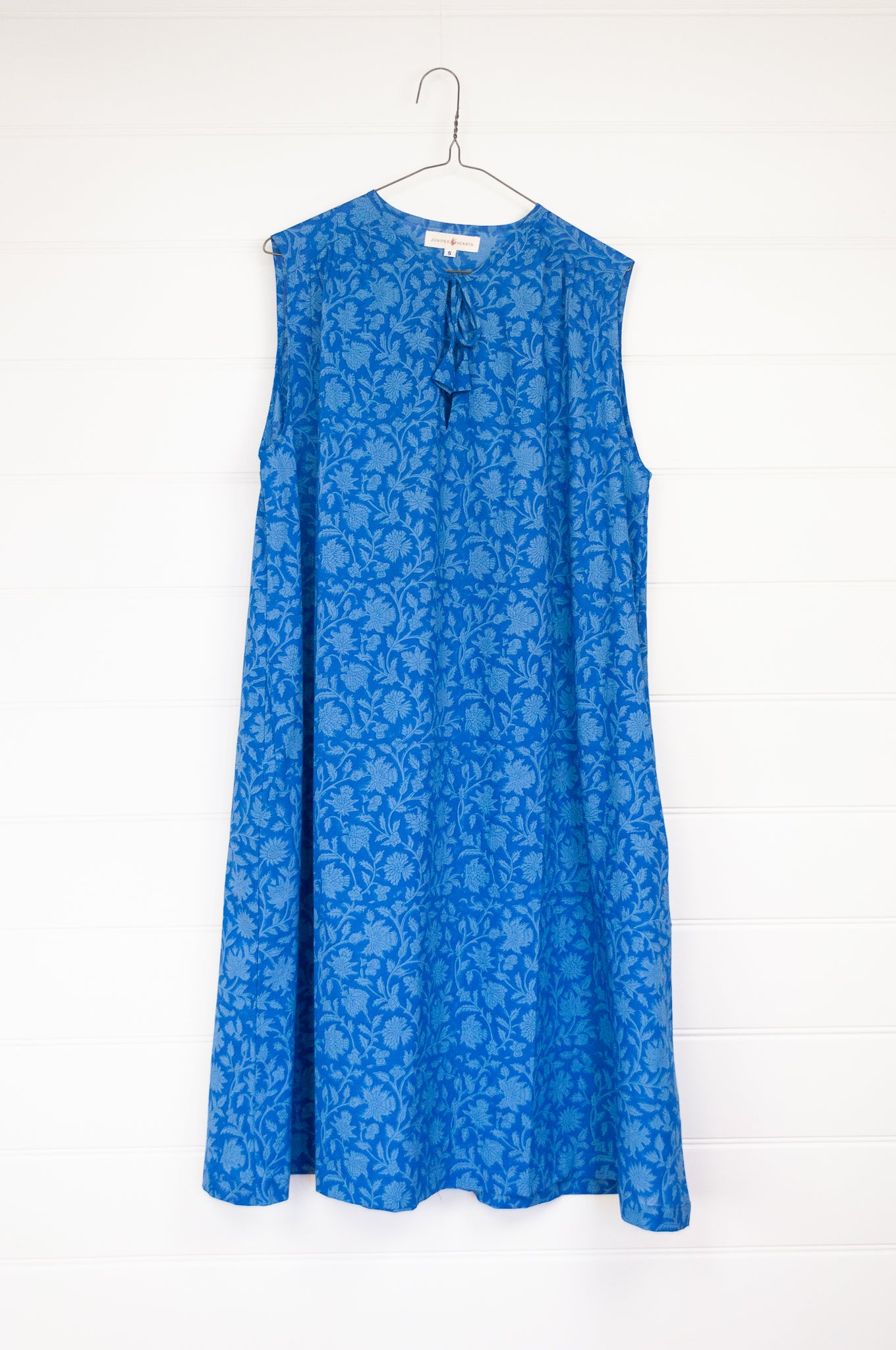 Juniper Hearth Stella dress in cornflower blue blockprint floral cotton, A-line sleeveless with front ties.