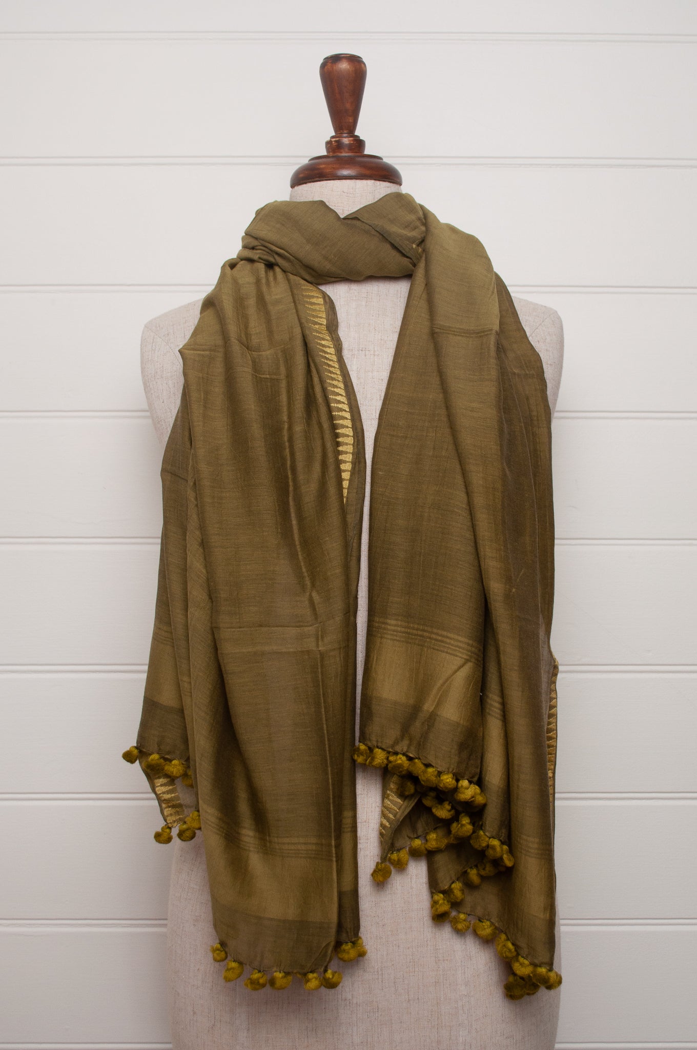Silk and cotton scarf with pom poms in olive green.