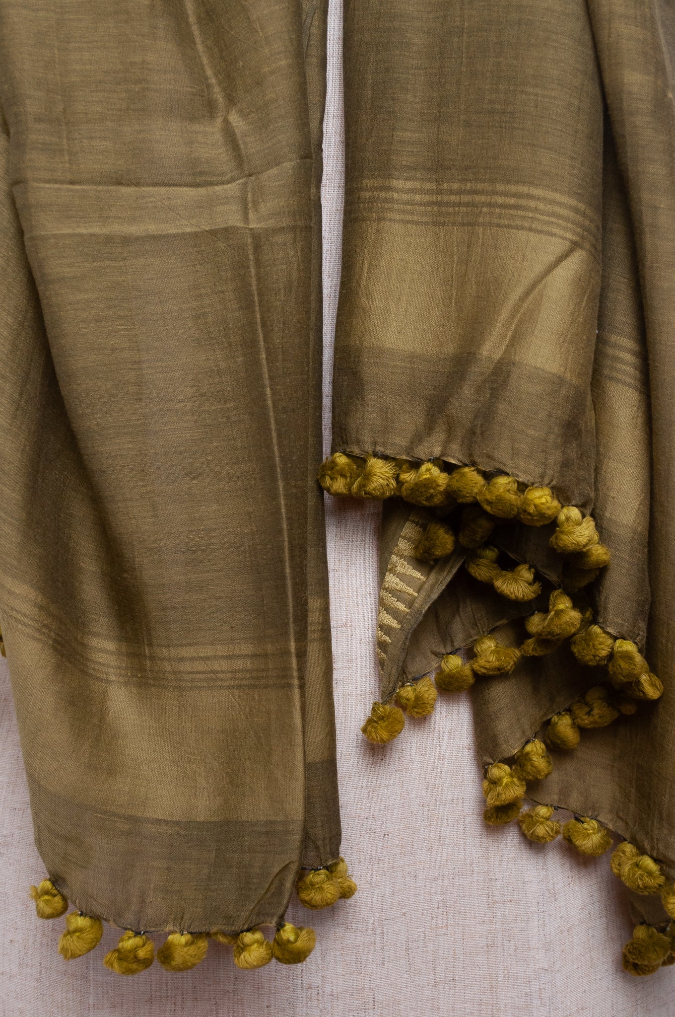 Silk and cotton scarf with pom poms in olive green.
