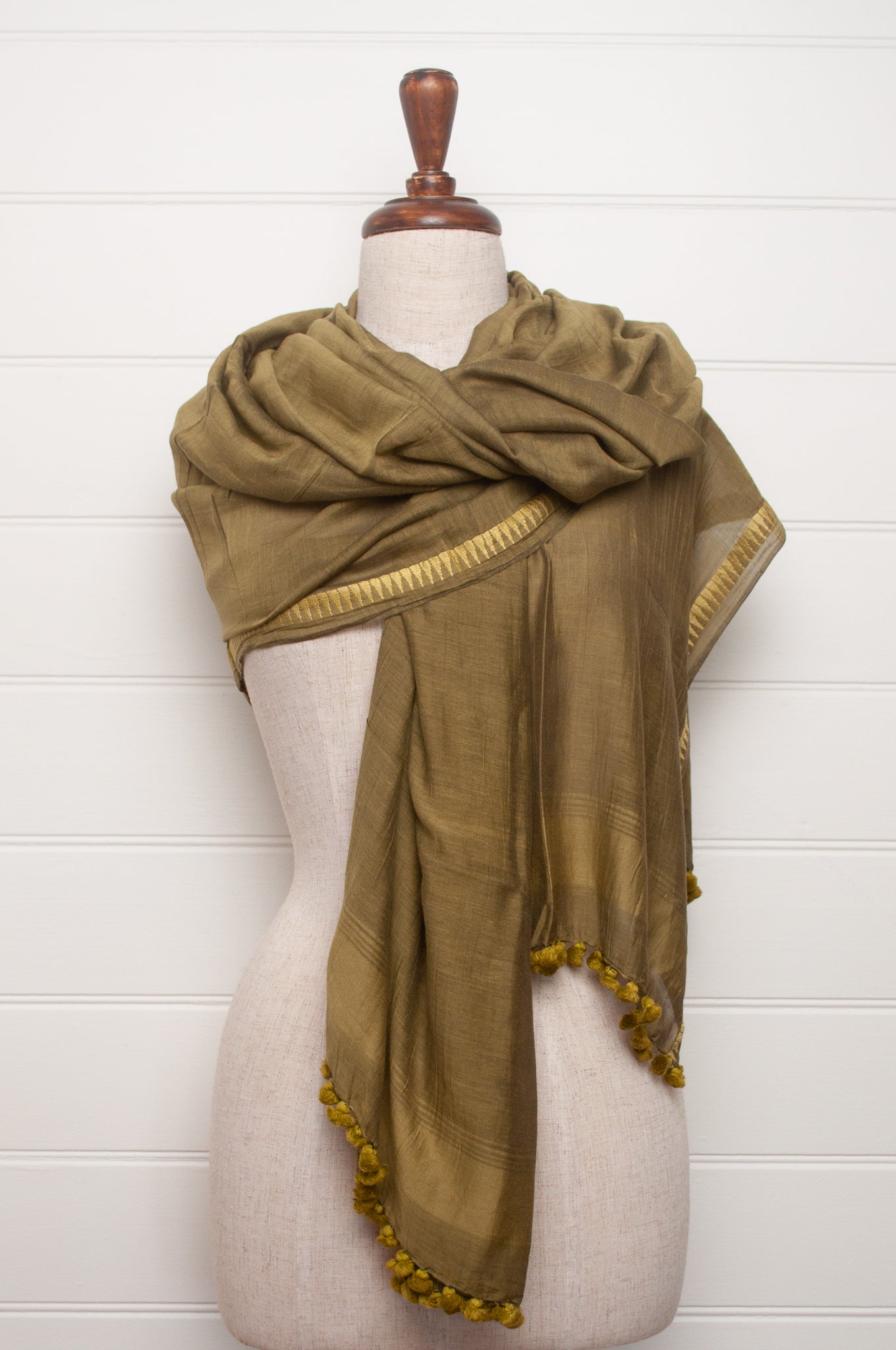 Silk and cotton scarf with pom poms in olive green.