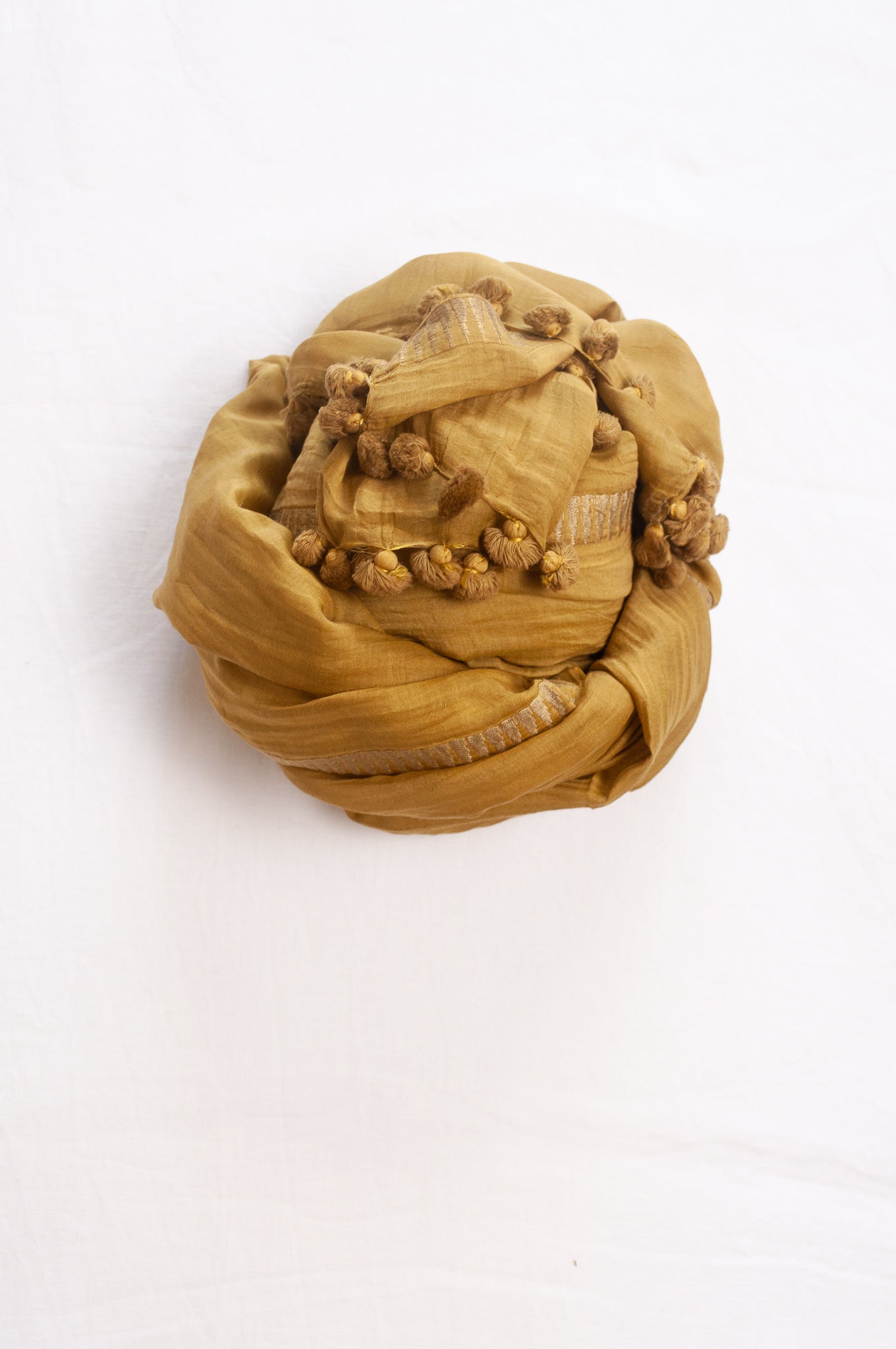 Silk and cotton scarf with pom poms in mustard yellow.