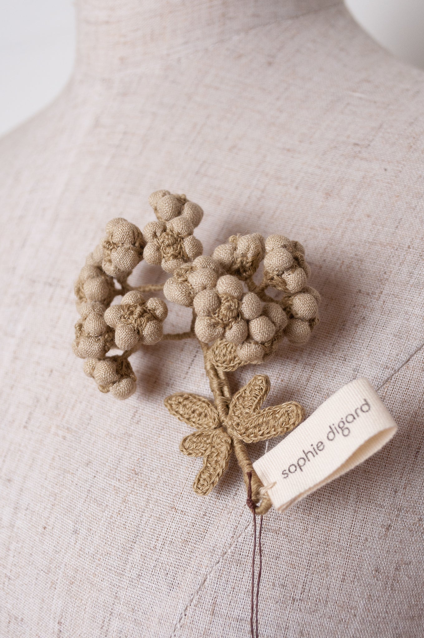 Handcrafted brooch by Sophie Digard, featuring embroidered flowers in thyme green linen.