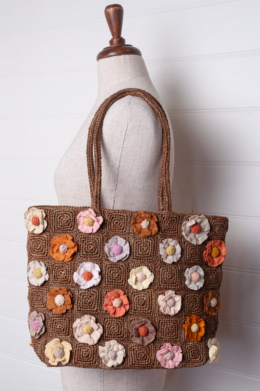 Sophie Digard crocheted raffia bag in tan with appliqued and embroidered linen flowers in warm neutrals.