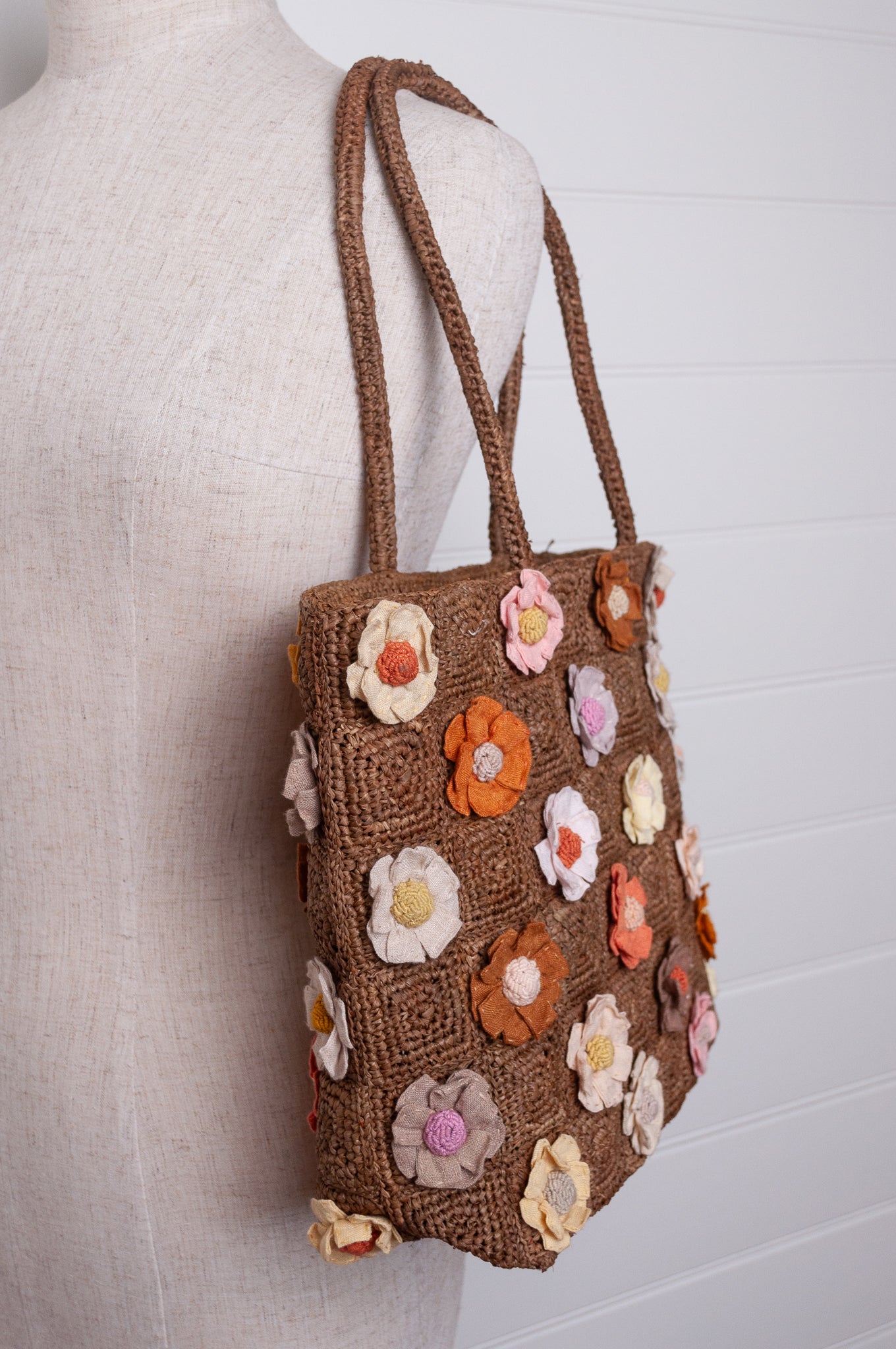 Sophie Digard crocheted raffia bag in tan with appliqued and embroidered linen flowers in warm neutrals.