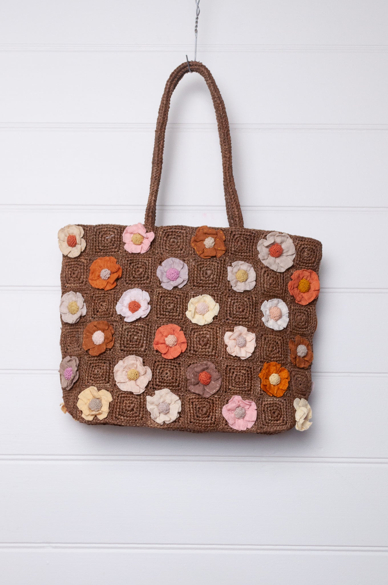 Sophie Digard crocheted raffia bag in tan with appliqued and embroidered linen flowers in warm neutrals.