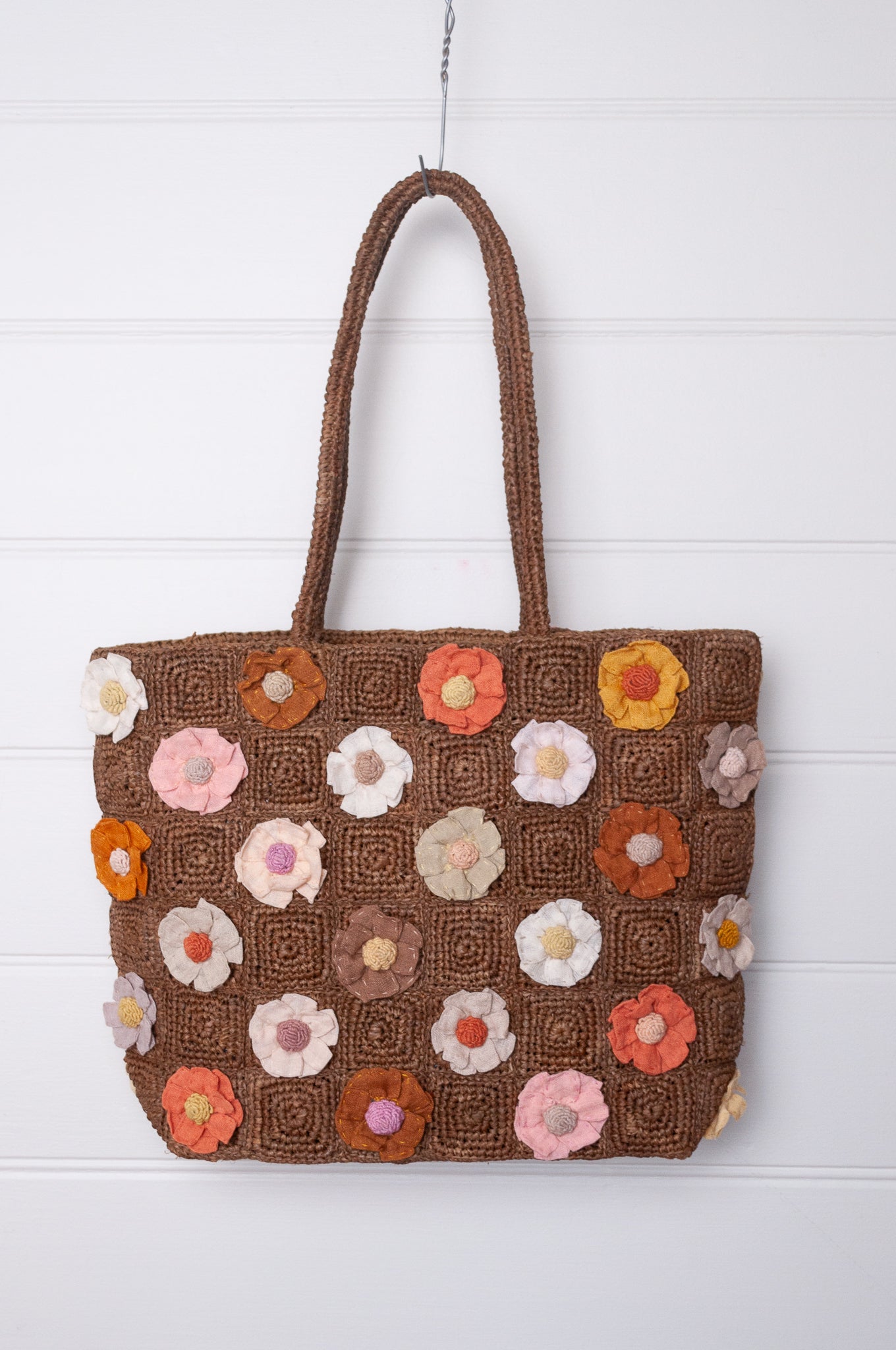 Sophie Digard crocheted raffia bag in tan with appliqued and embroidered linen flowers in warm neutrals.