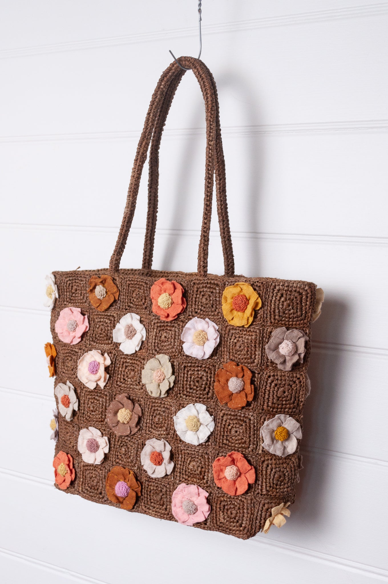 Sophie Digard crocheted raffia bag in tan with appliqued and embroidered linen flowers in warm neutrals.