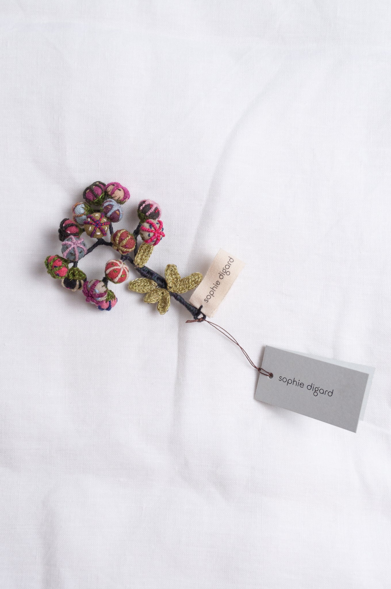Handcrafted brooch by Sophie Digard, featuring small embroidered button flowers in linen.