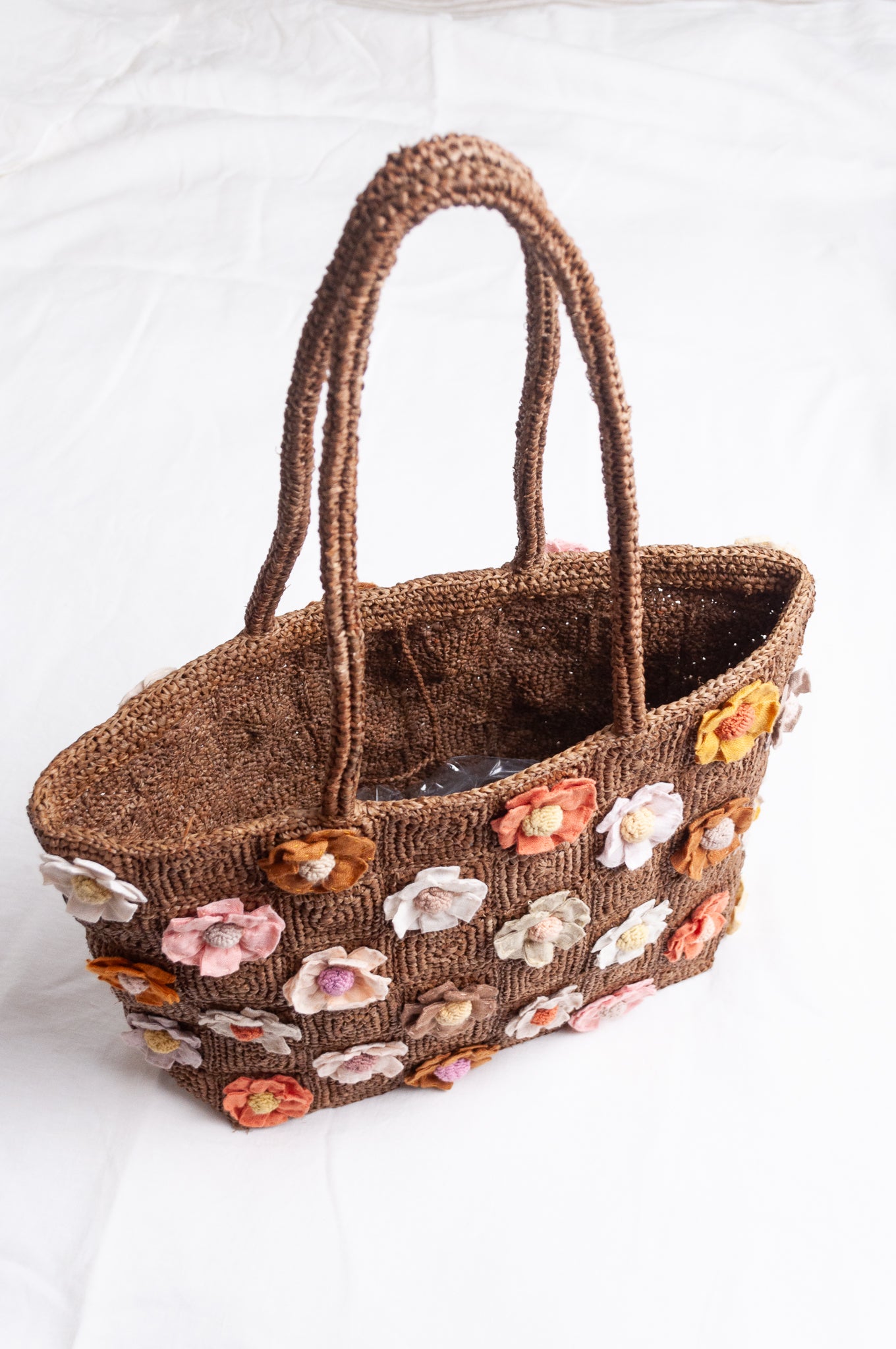 Sophie Digard crocheted raffia bag in tan with appliqued and embroidered linen flowers in warm neutrals.