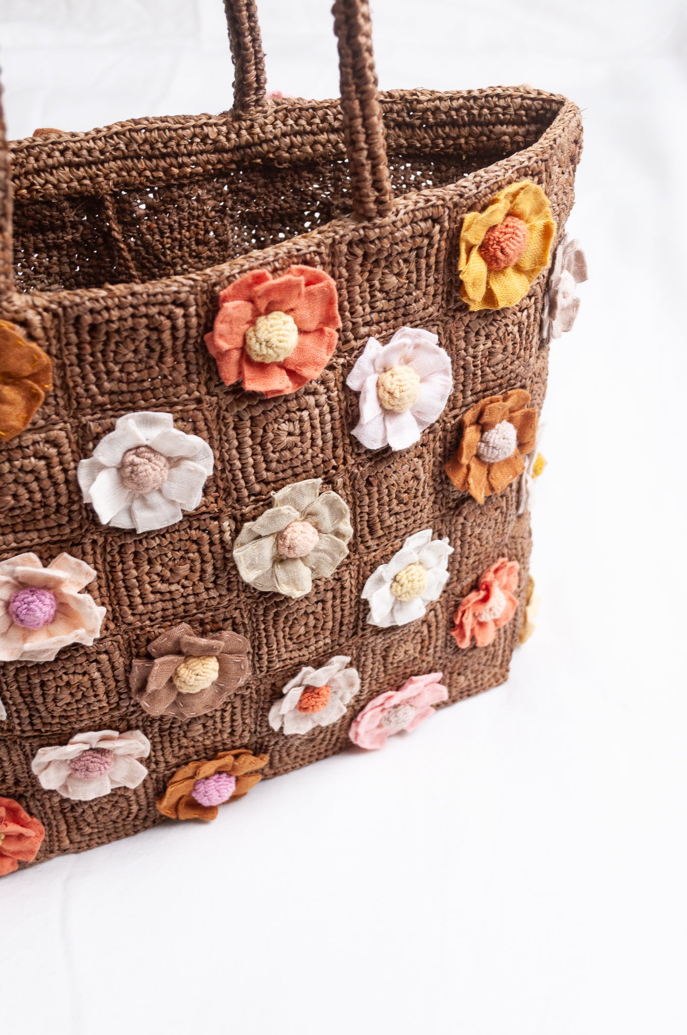 Sophie Digard crocheted raffia bag in tan with appliqued and embroidered linen flowers in warm neutrals.
