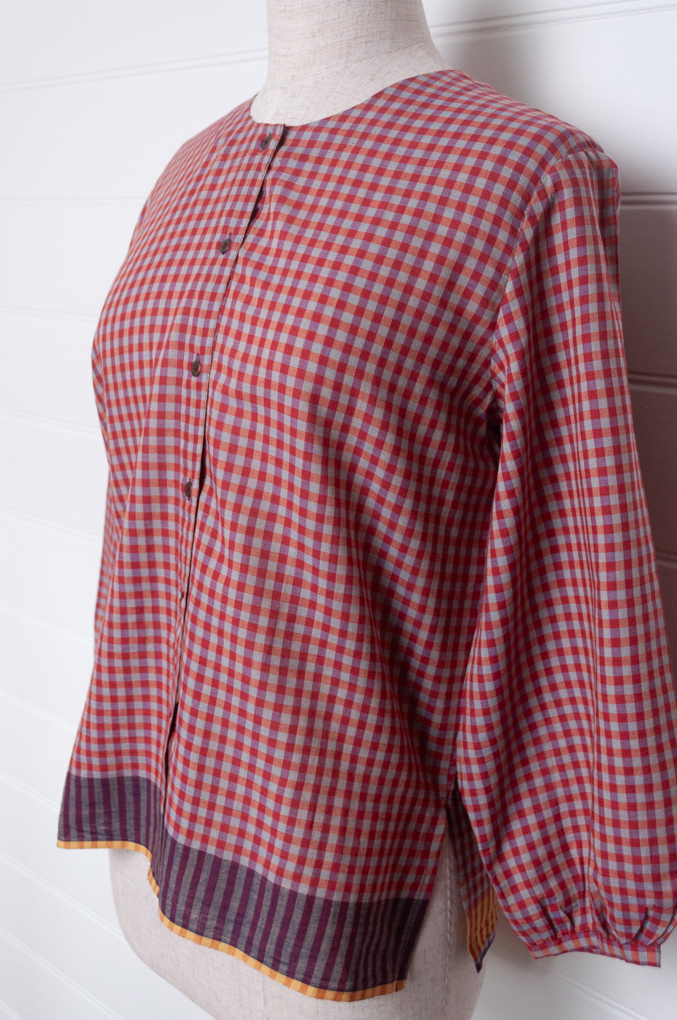 Handloom check cotton button up round neck blouse with long sleeves and selvedge hem detail.