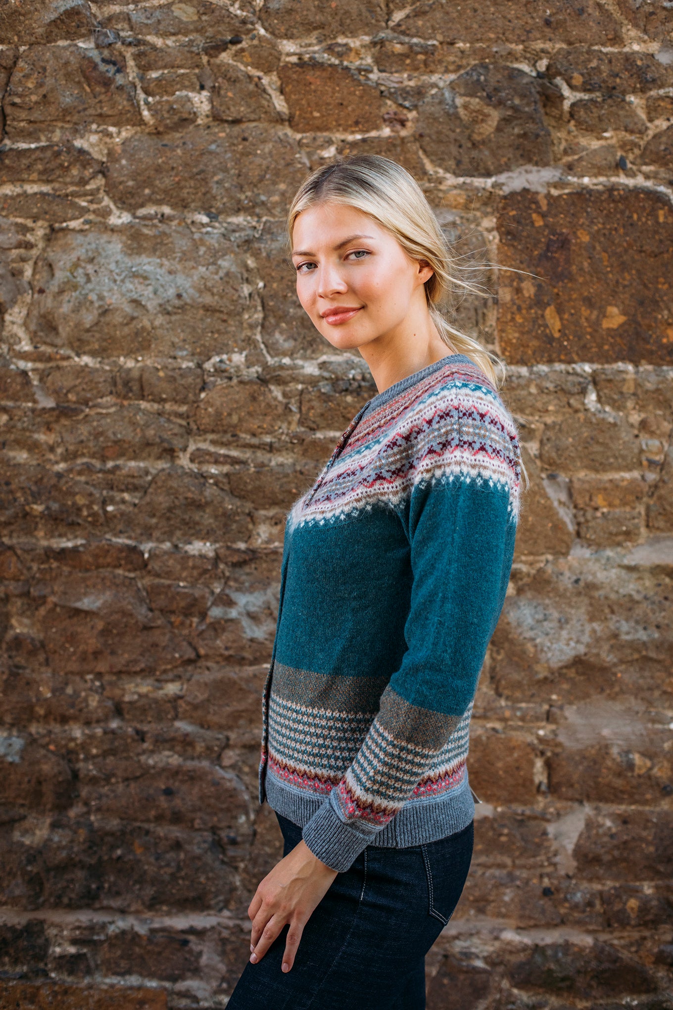 Eribé Alpine cardigan in Lugano, features a rich teal body, with highlights in rust, burgundy, bright pink, ecru and soft blue grey.