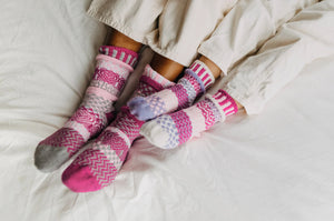 Solmate baby socks, two pairs and a spare knit from recycled cotton yarn in light pink, pink, purple and white.