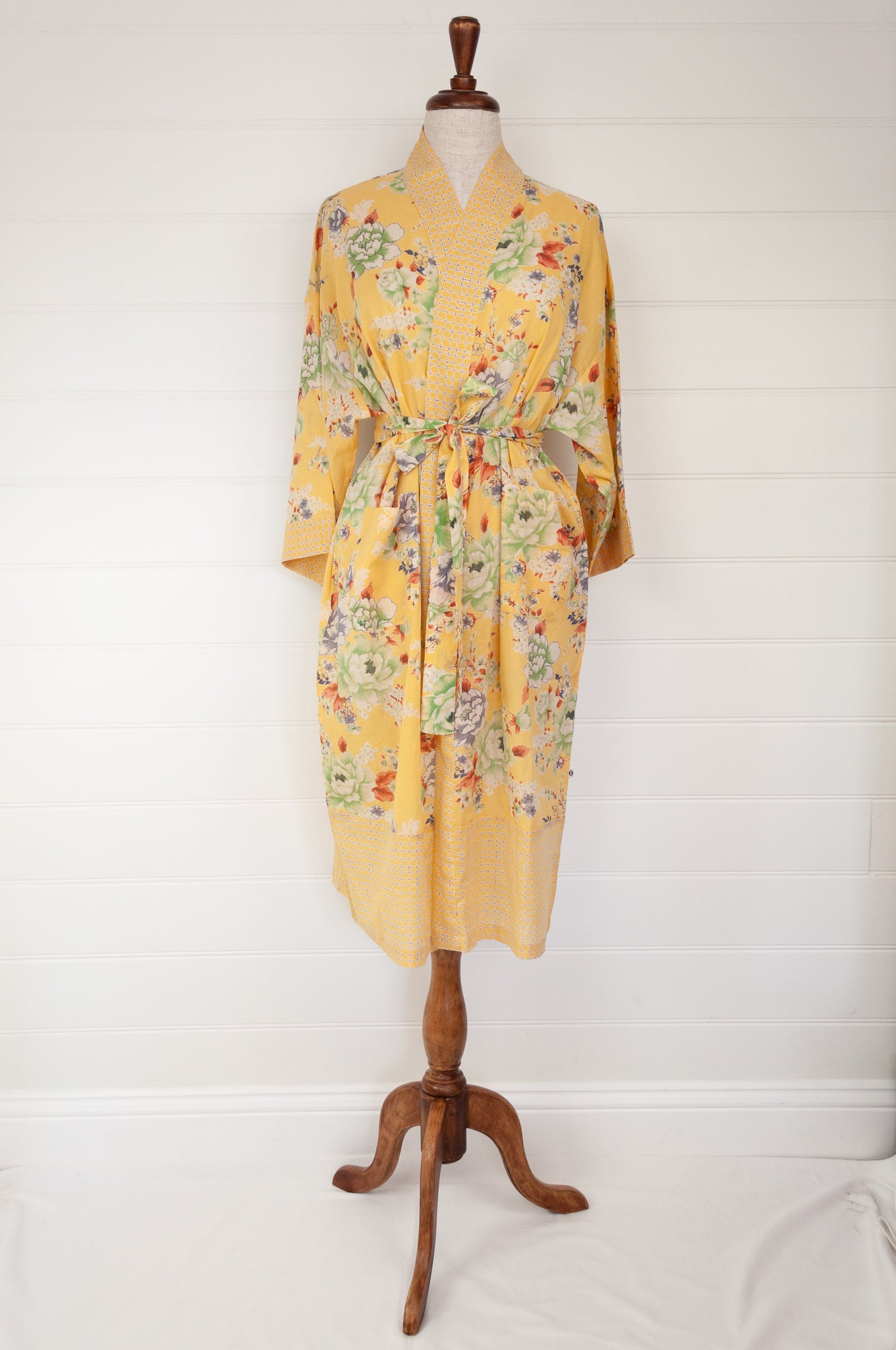 100% fine cotton voile kimono gown, screen printed by hand, peony floral print in shades of green, white, orange and grey on a butter yellow background, contrast trim. Ethically made.