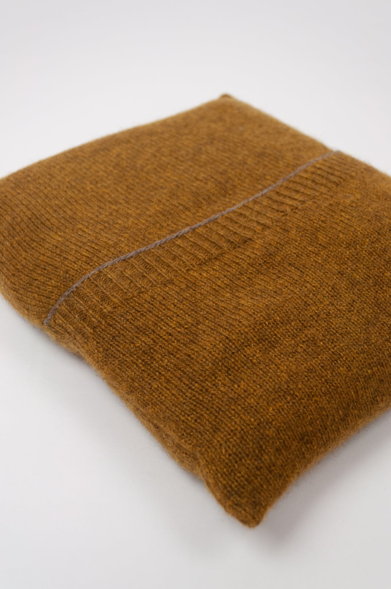 Juniper Hearth baby yak wool poncho in Maize, a deep mustard gold (close up, folded in pouch).