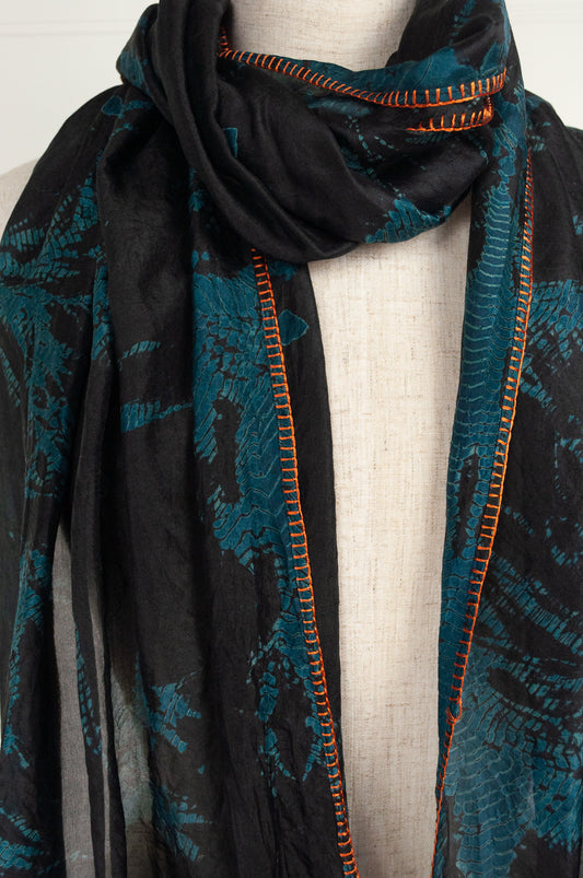 Neeru Kumar fine silk shibori dyed scarf, black with teal green patterning, edge stitched and tassels in neon orange.