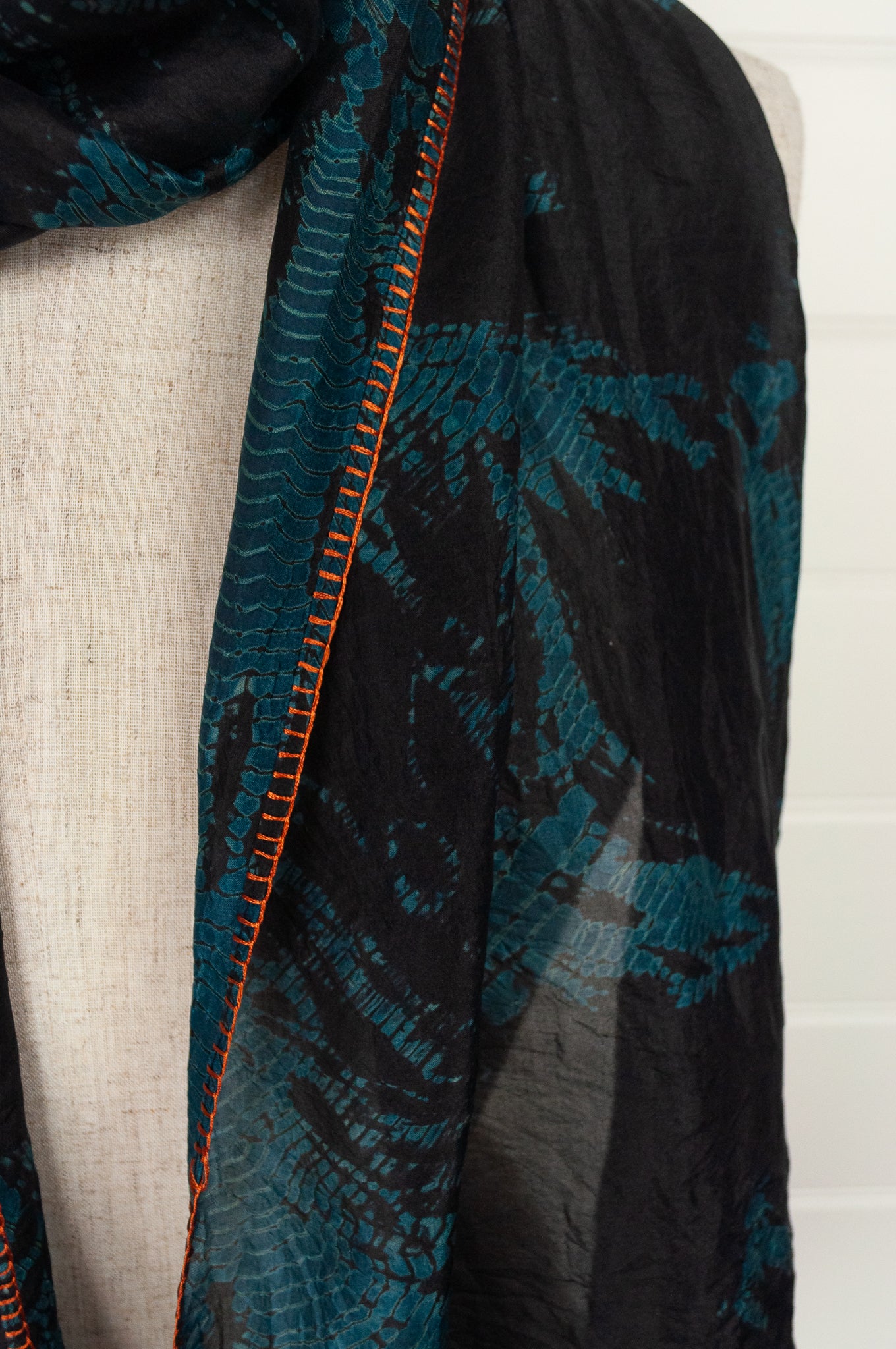 Neeru Kumar fine silk shibori dyed scarf, black with teal green patterning, edge stitched and tassels in neon orange.