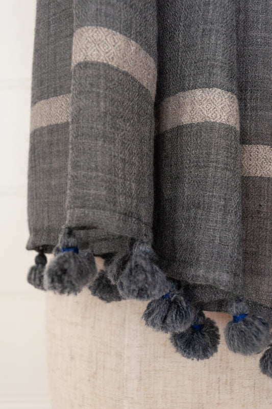 Juniper Hearth woven merino wool scarf, lightweight and very soft, melange dye from charcoal to sapphire blue, with handmade pompoms.