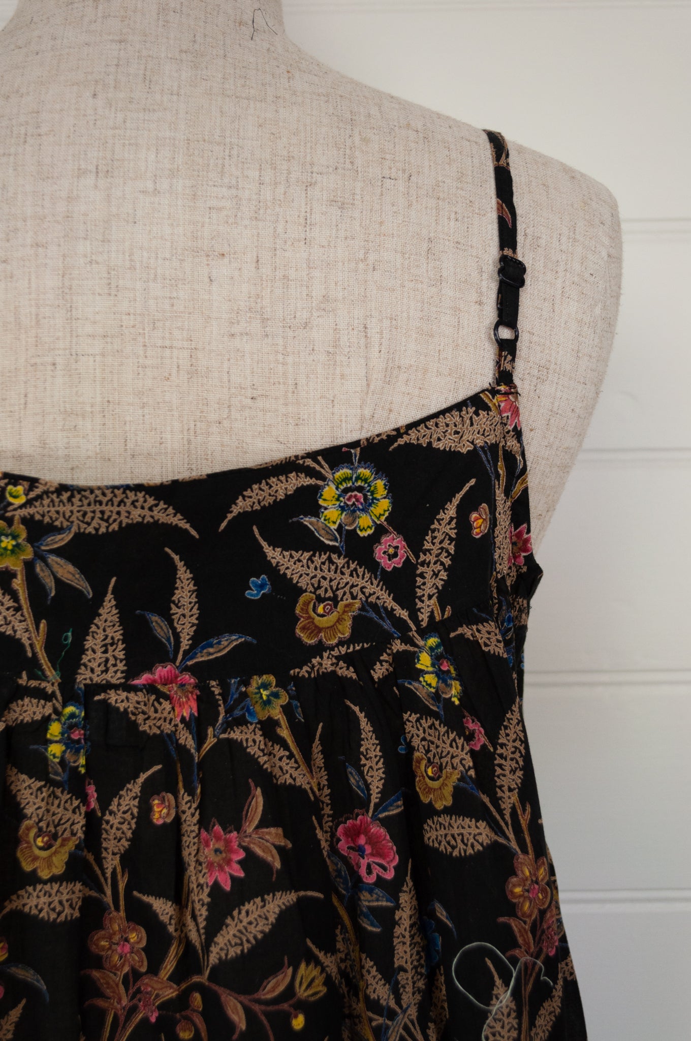 Ethically made pure cotton voile summer nightdress with adjustable straps and pintucked yoke, this nightie is in a wildflower print on black with broderie edging (back view adjustable strap).