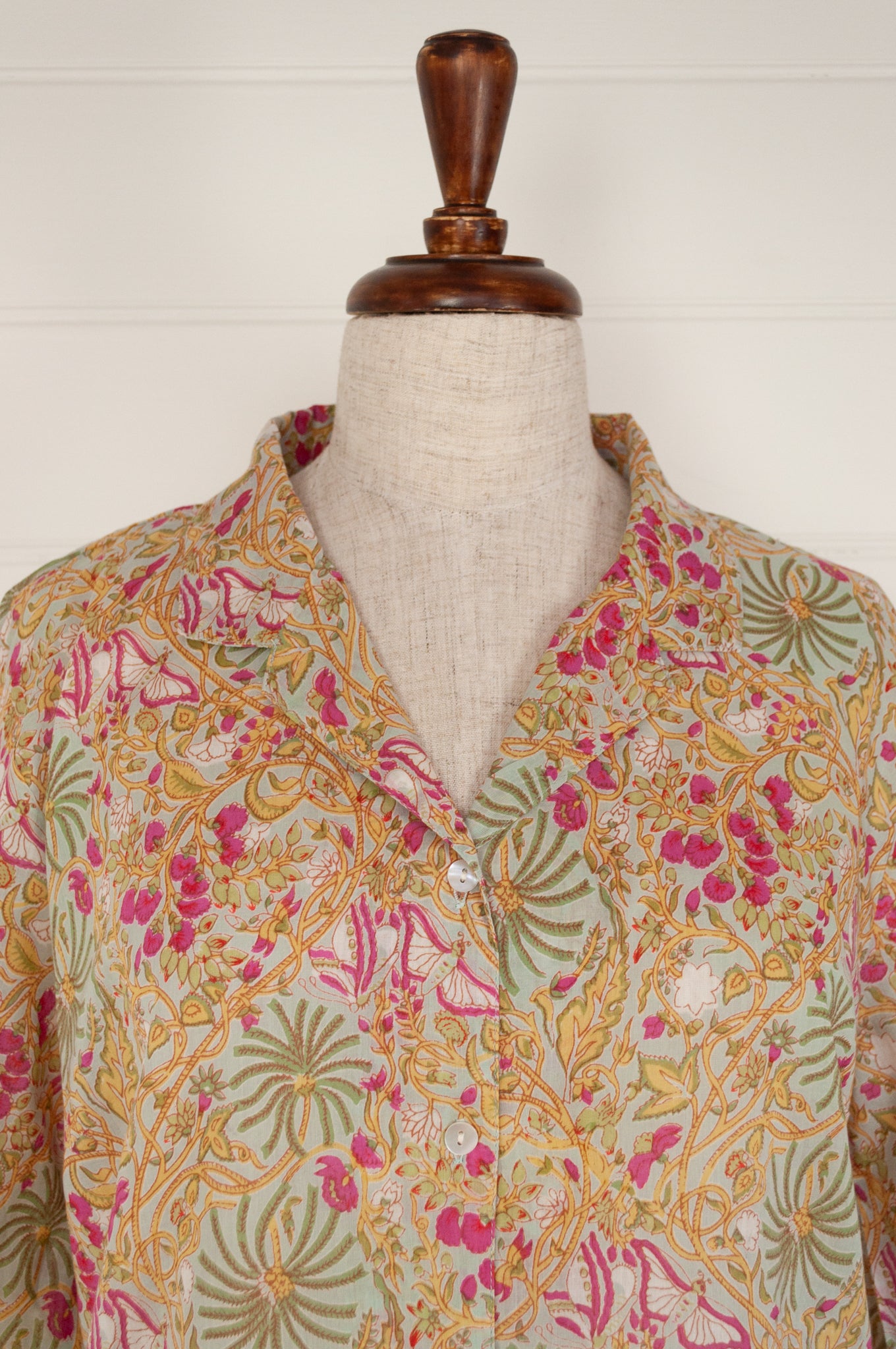 Ethically made cotton voile pyjamas featuring a print of palm trees, vines and butterflies in sage green, lemon and raspberry pink on a soft lime green background.