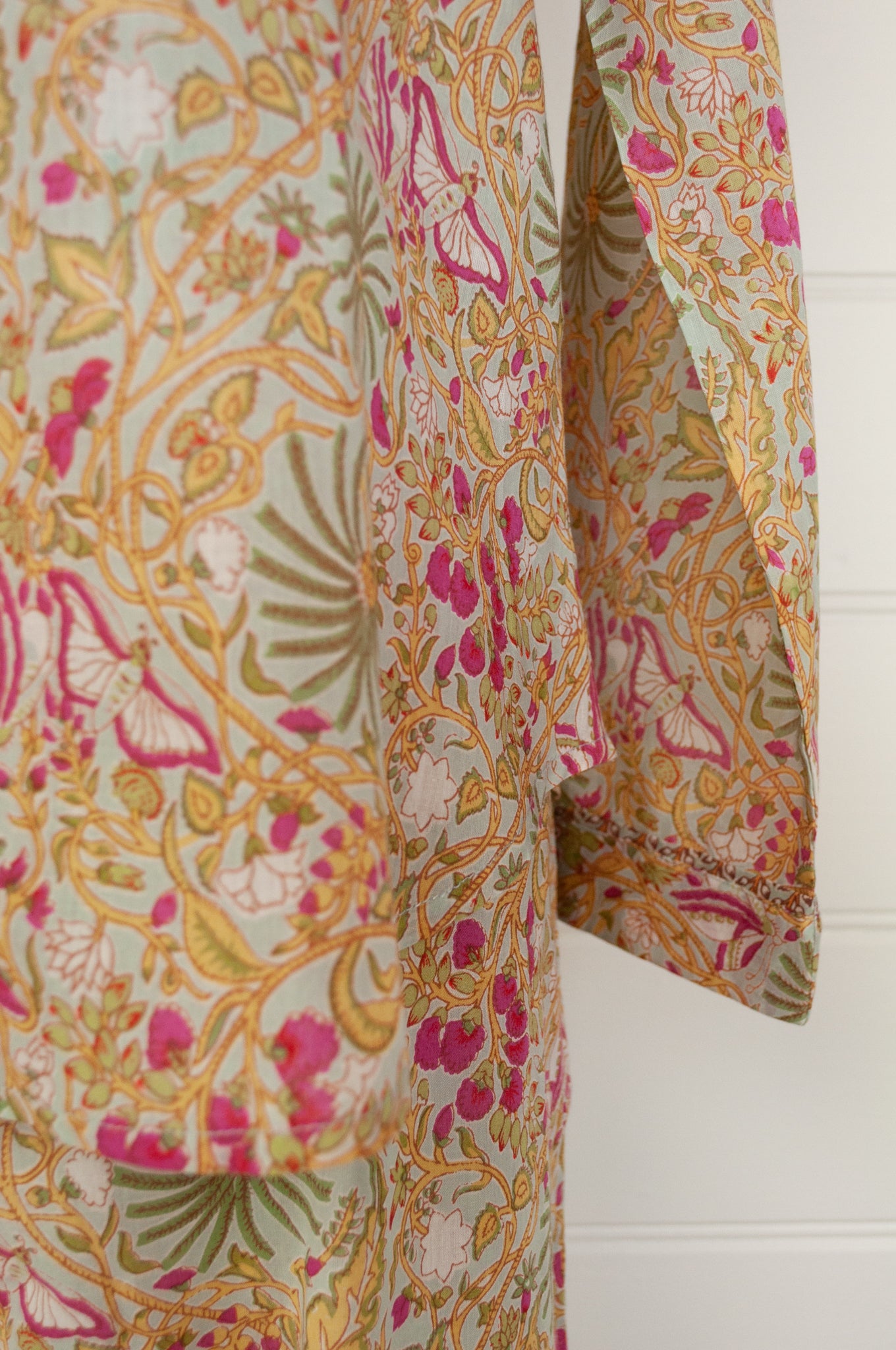 Ethically made cotton voile pyjamas featuring a print of palm trees, vines and butterflies in sage green, lemon and raspberry pink on a soft lime green background.