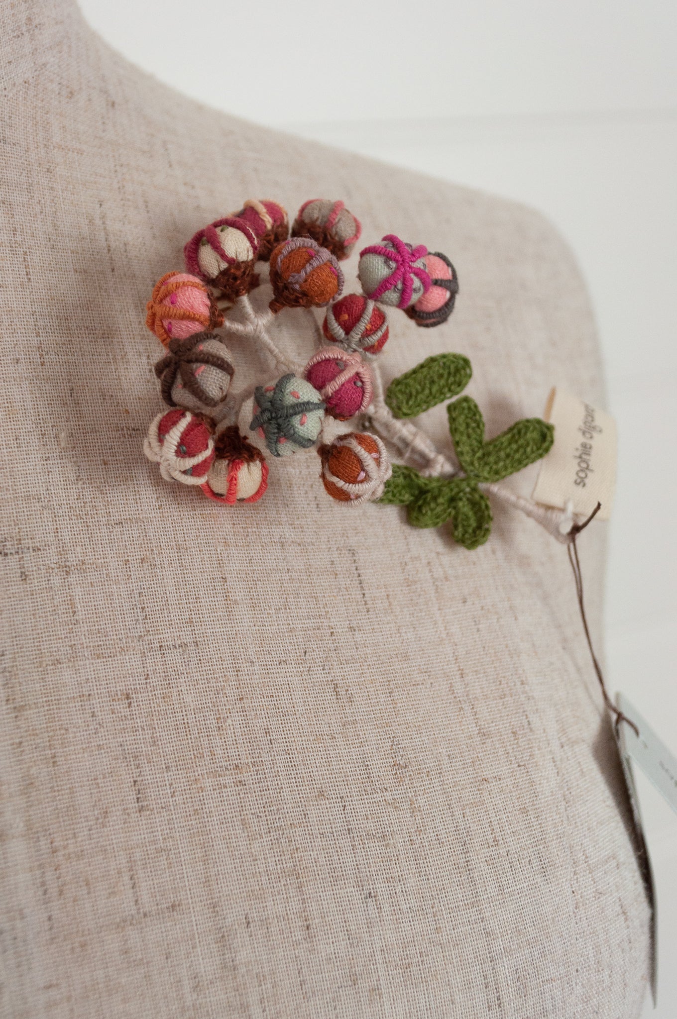Sophie Digard hand made embroidered and crocheted linen flower brooch in light aqua, pinks and reds.