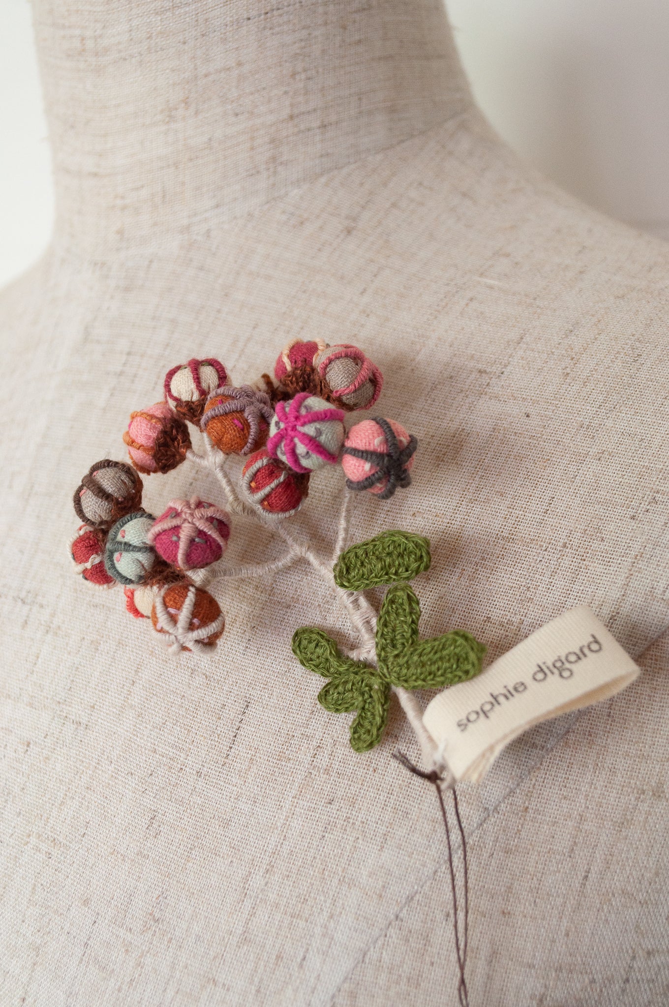 Sophie Digard hand made embroidered and crocheted linen flower brooch in light aqua, pinks and reds.