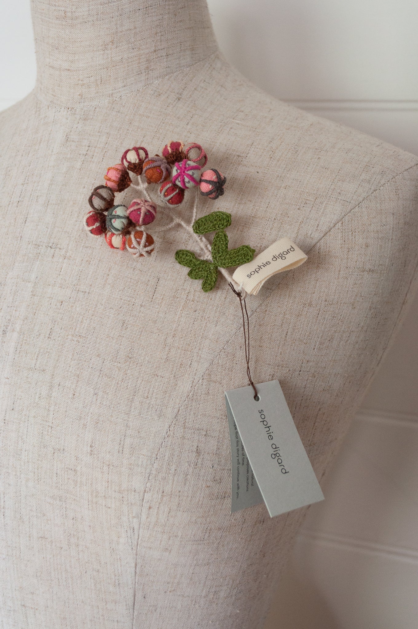 Sophie Digard hand made embroidered and crocheted linen flower brooch in light aqua, pinks and reds.