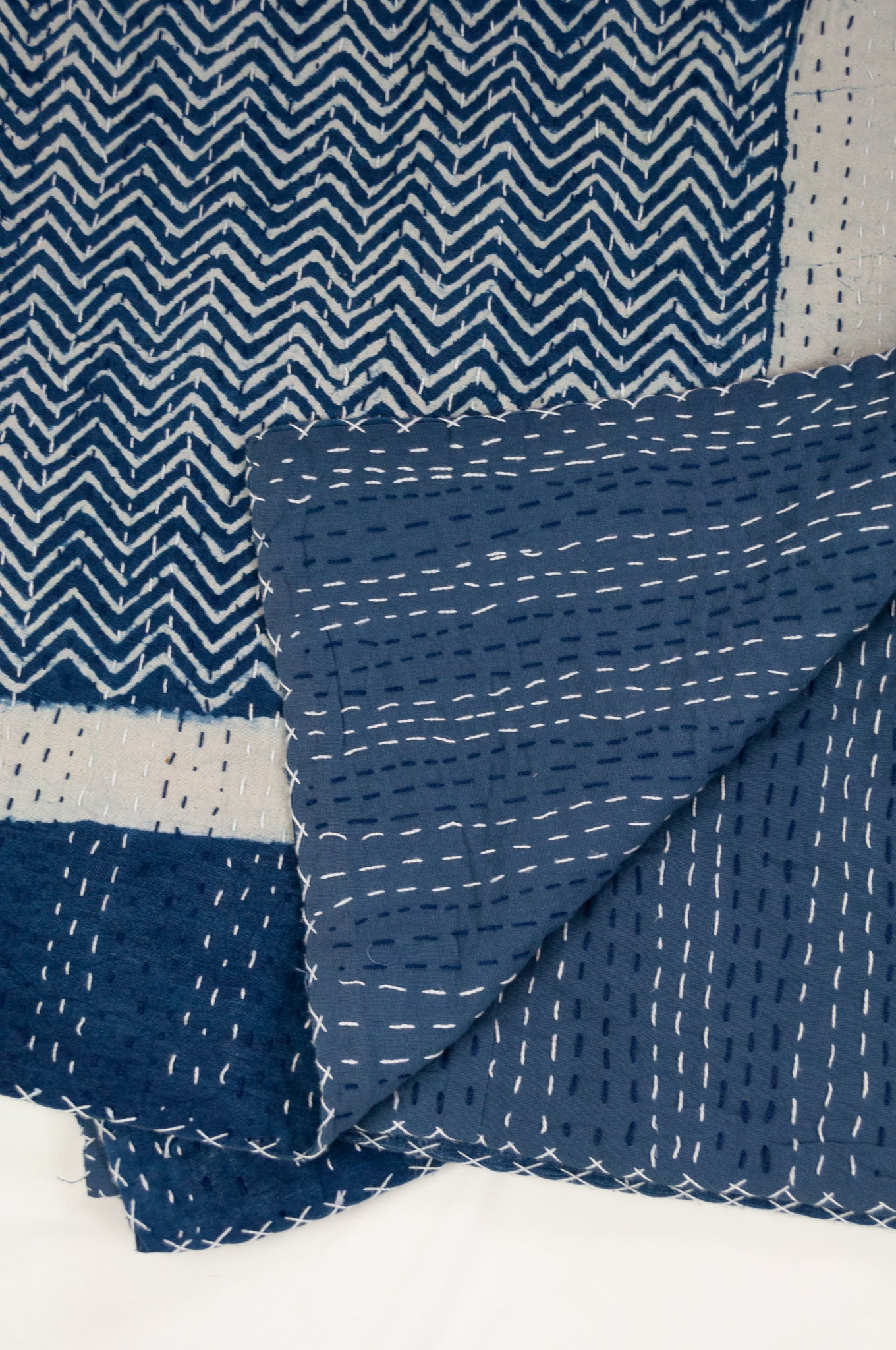Block printed in indigo, blue and white kantha quilt hand made in Jaipur, featuring chevron pattern and plain blue and white border.