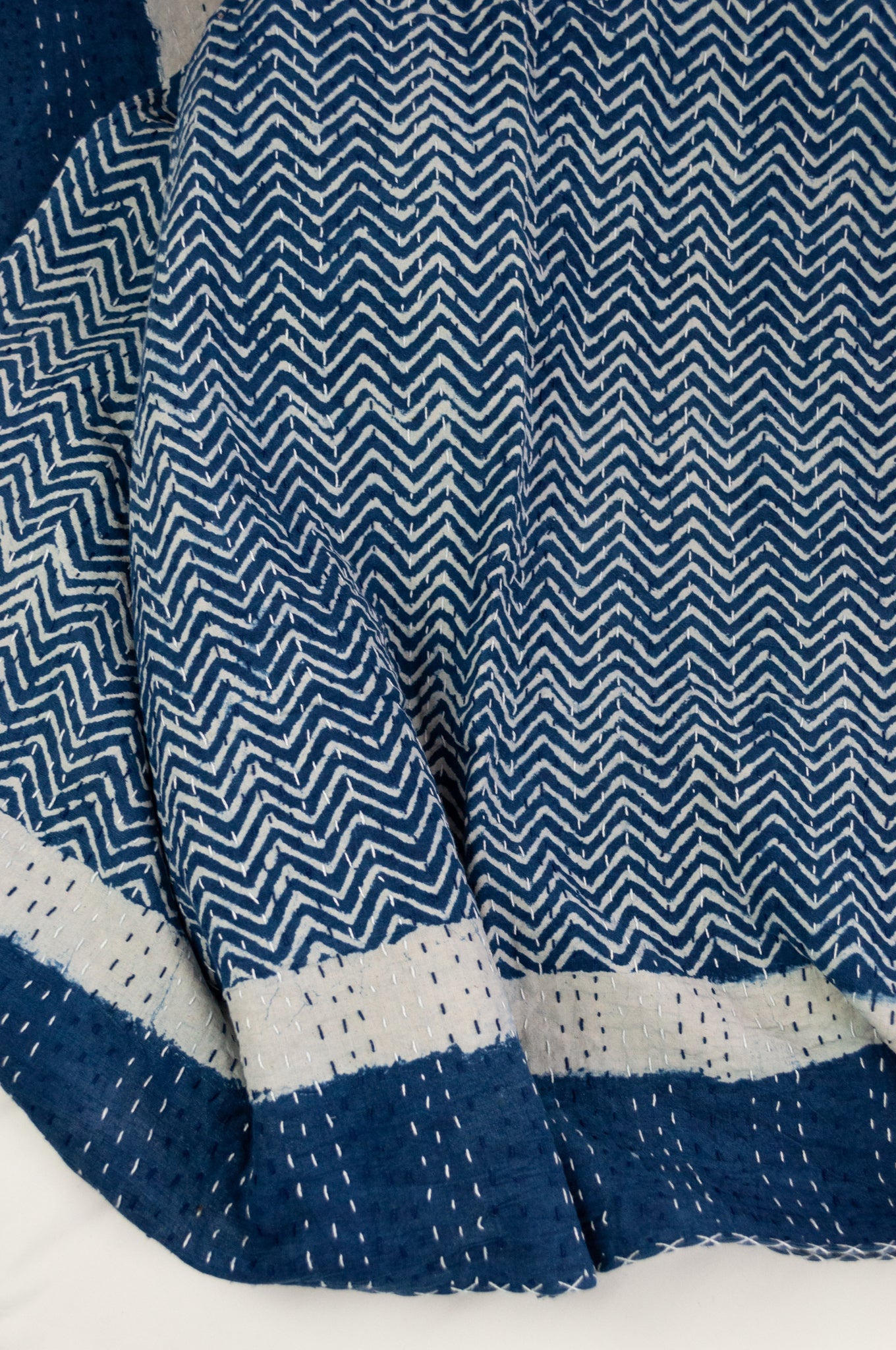 Block printed in indigo, blue and white kantha quilt hand made in Jaipur, featuring chevron pattern and plain blue and white border.