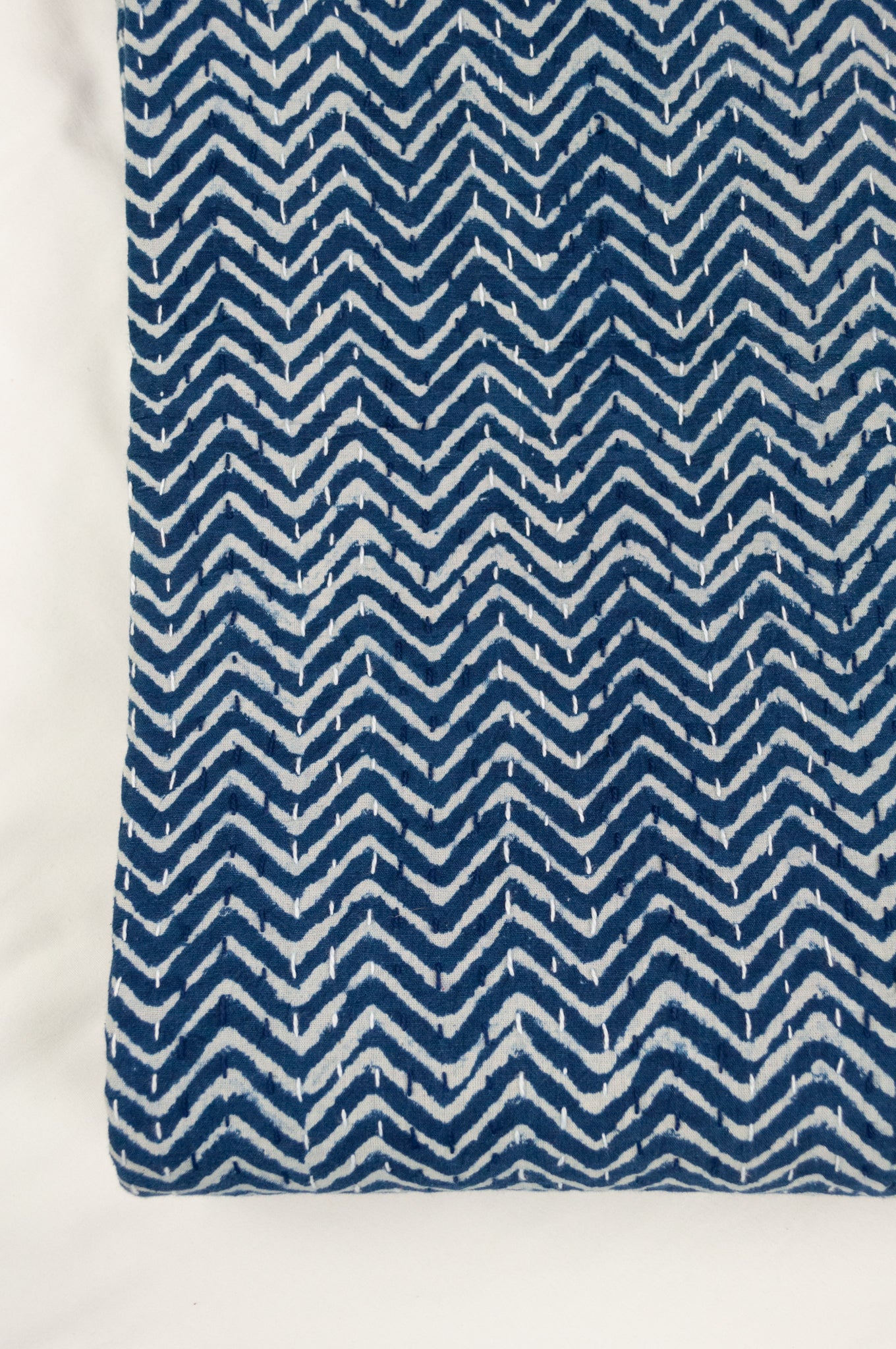 Block printed in indigo, blue and white kantha quilt hand made in Jaipur, featuring chevron pattern and plain blue and white border.