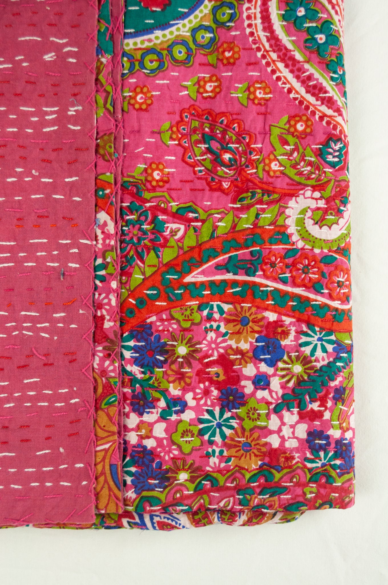 Handstitched cotton kantha quilt, a colourful paisley on a deep pink background, with highlights in lime, emerald, turquoise, white, and tan