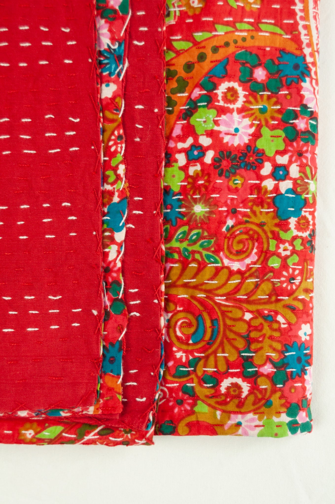 Handstitched cotton kantha quilt, a colourful paisley on a brilliant red background, with highlights in lime, emerald, turquoise, white, and tan